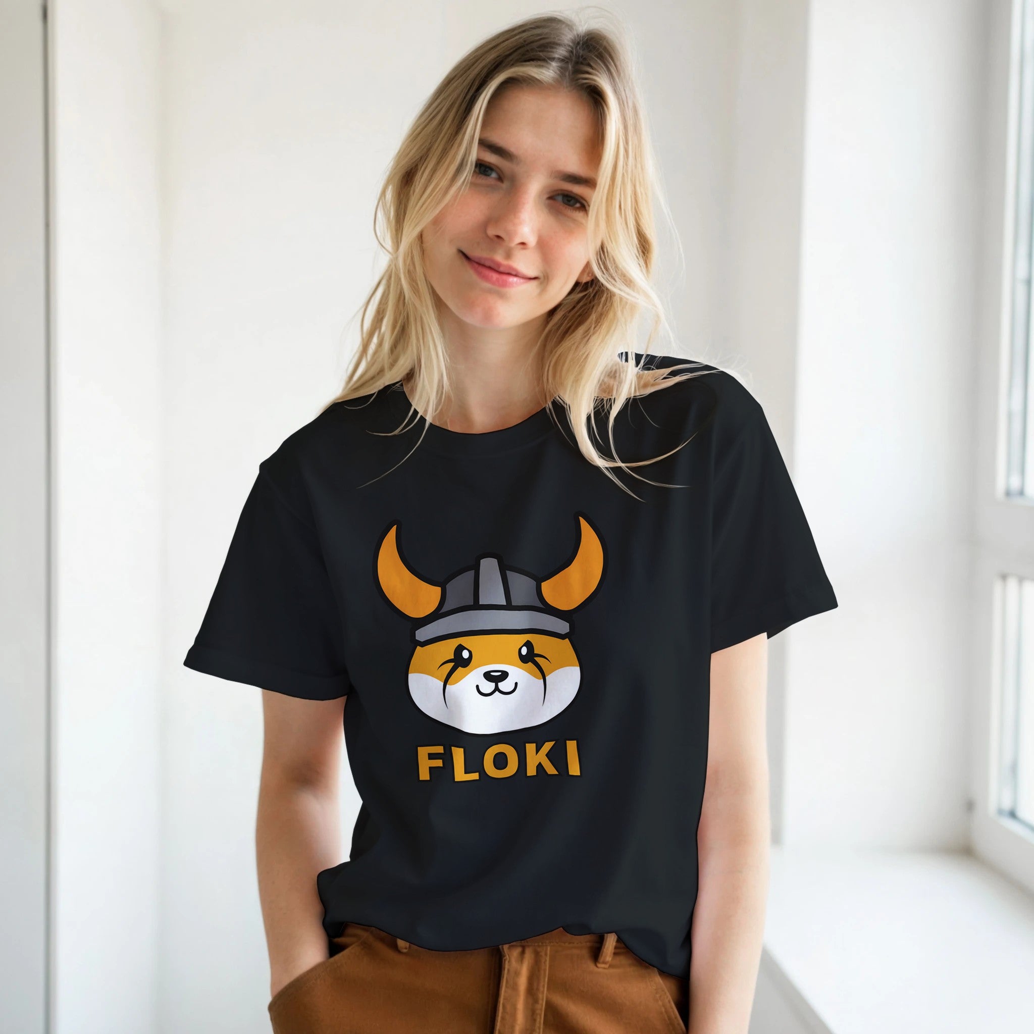 Person wearing a black t-shirt with a 'FLOKI' design, standing indoors.