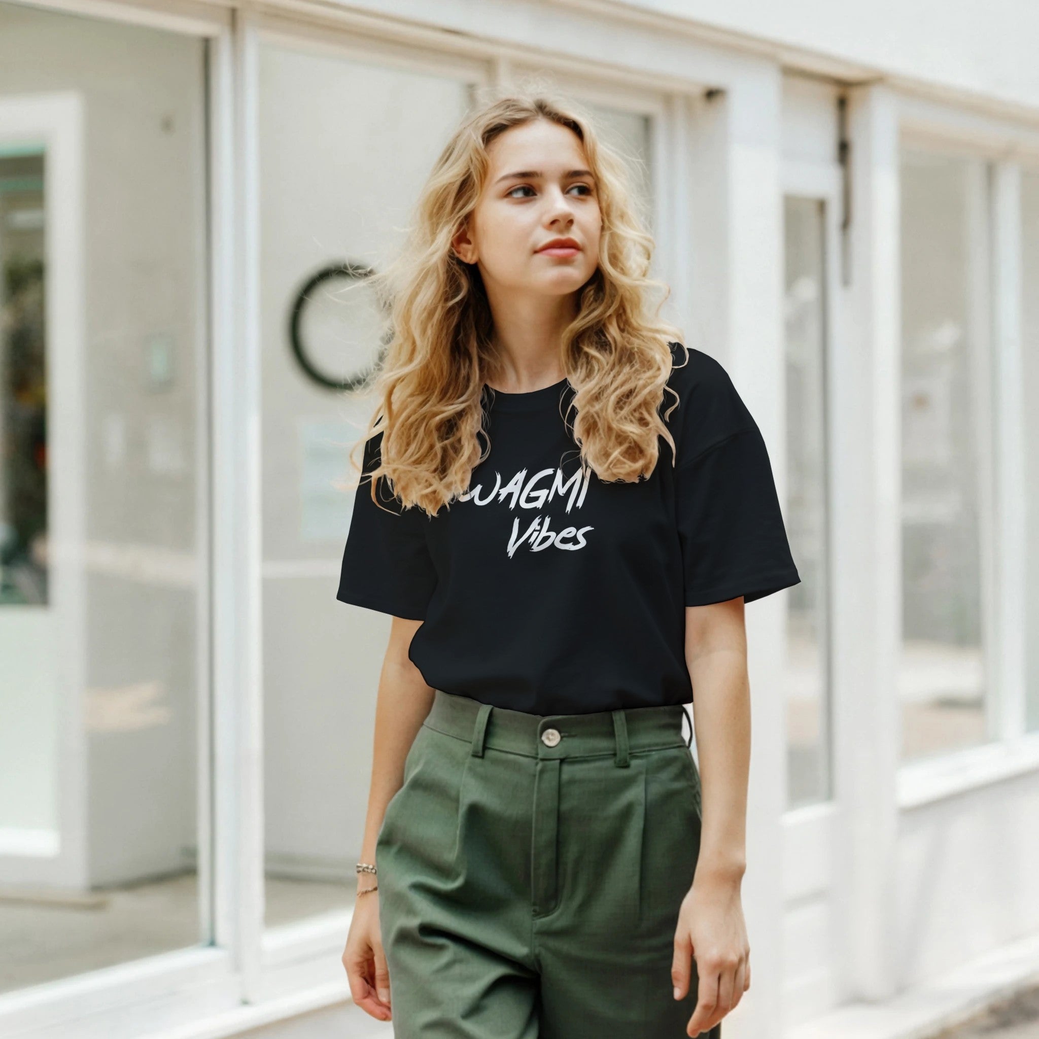 Woman wearing a black t-shirt with 'WAGMI Vibes' text, standing in front of a glass door.