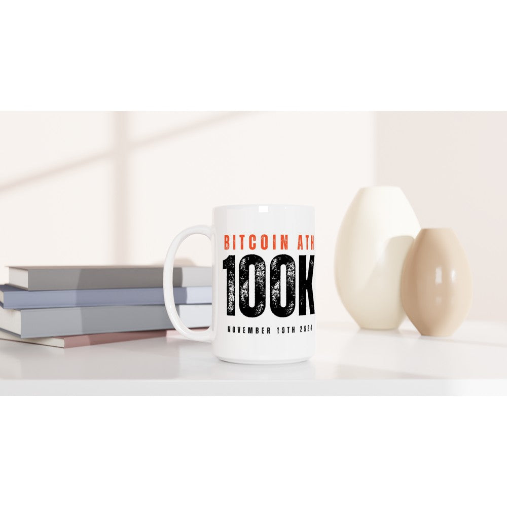 White mug with Bitcoin text on a white surface with books and decorative items