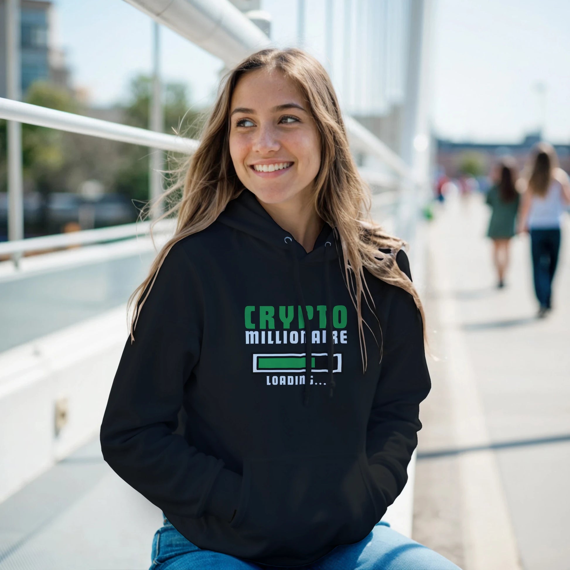 Woman wearing a black hoodie with 'Crypto Millionaire' text, sitting outdoors.