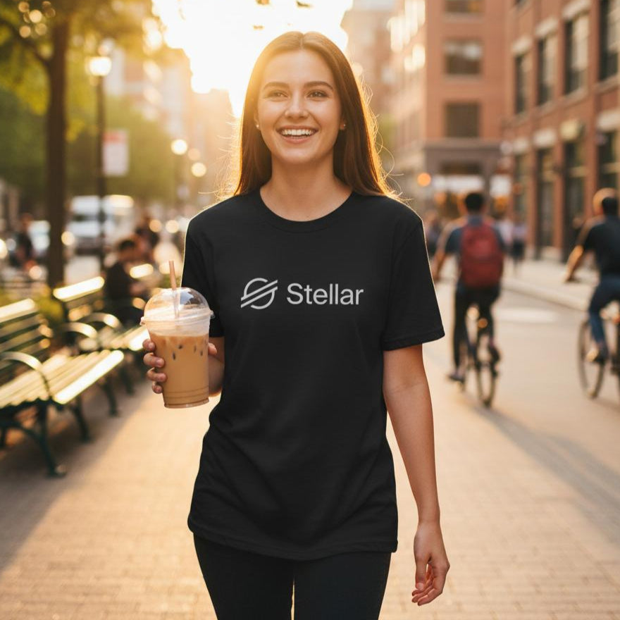 Woman holding a coffee cup and wearing a black Stellar t-shirt on a city street.