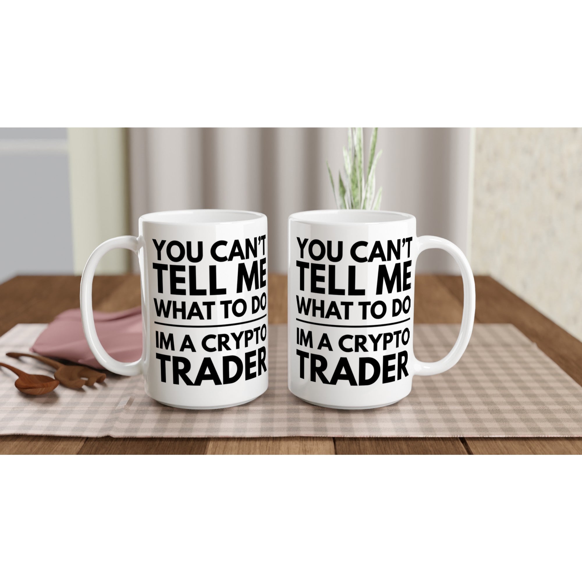 Two white mugs with black text on a wooden table.