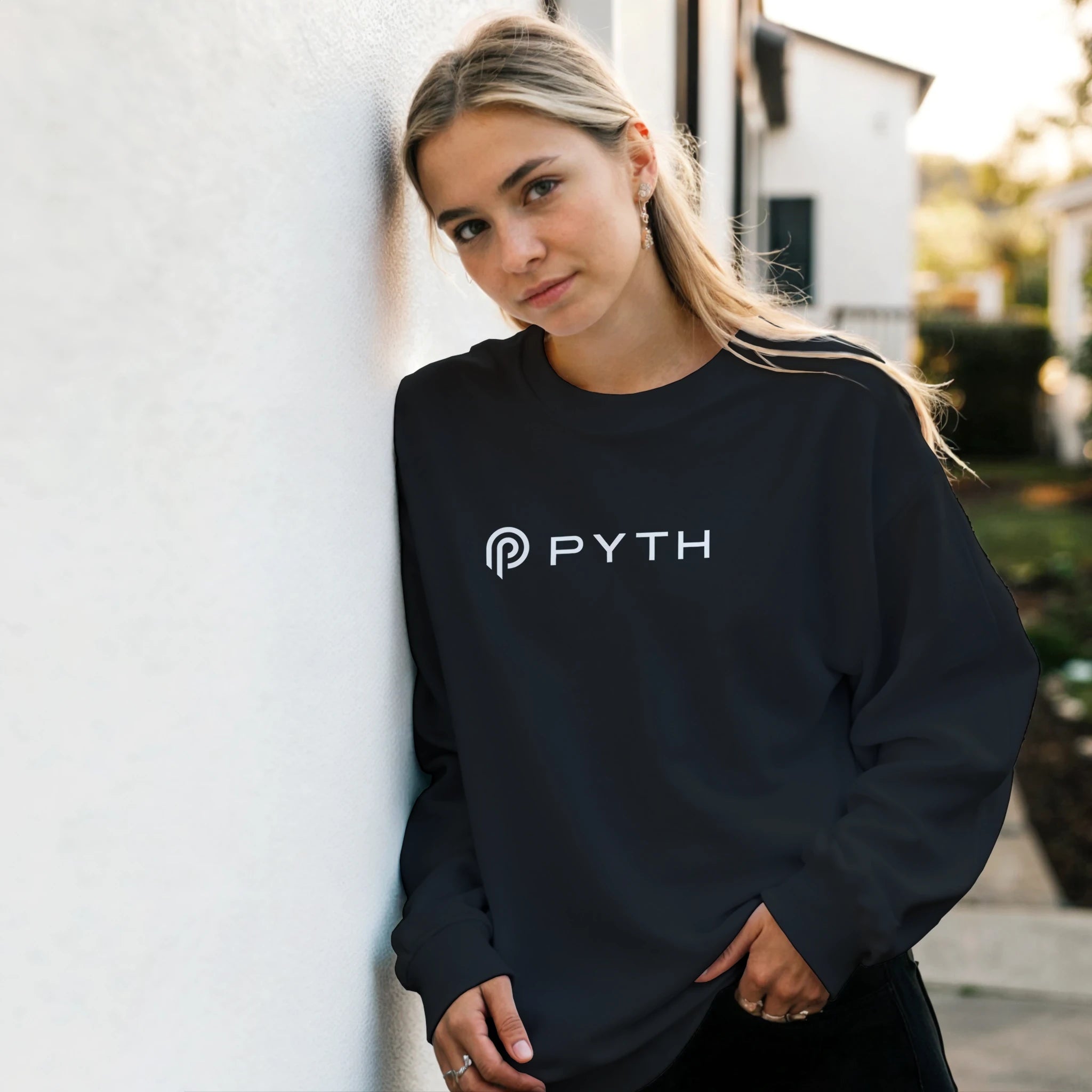 Person wearing a black sweatshirt with 'PYTH' logo outdoors.