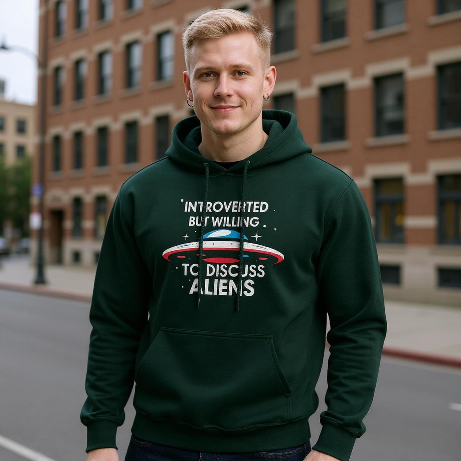 Man wearing a green hoodie with alien-themed text on a city street