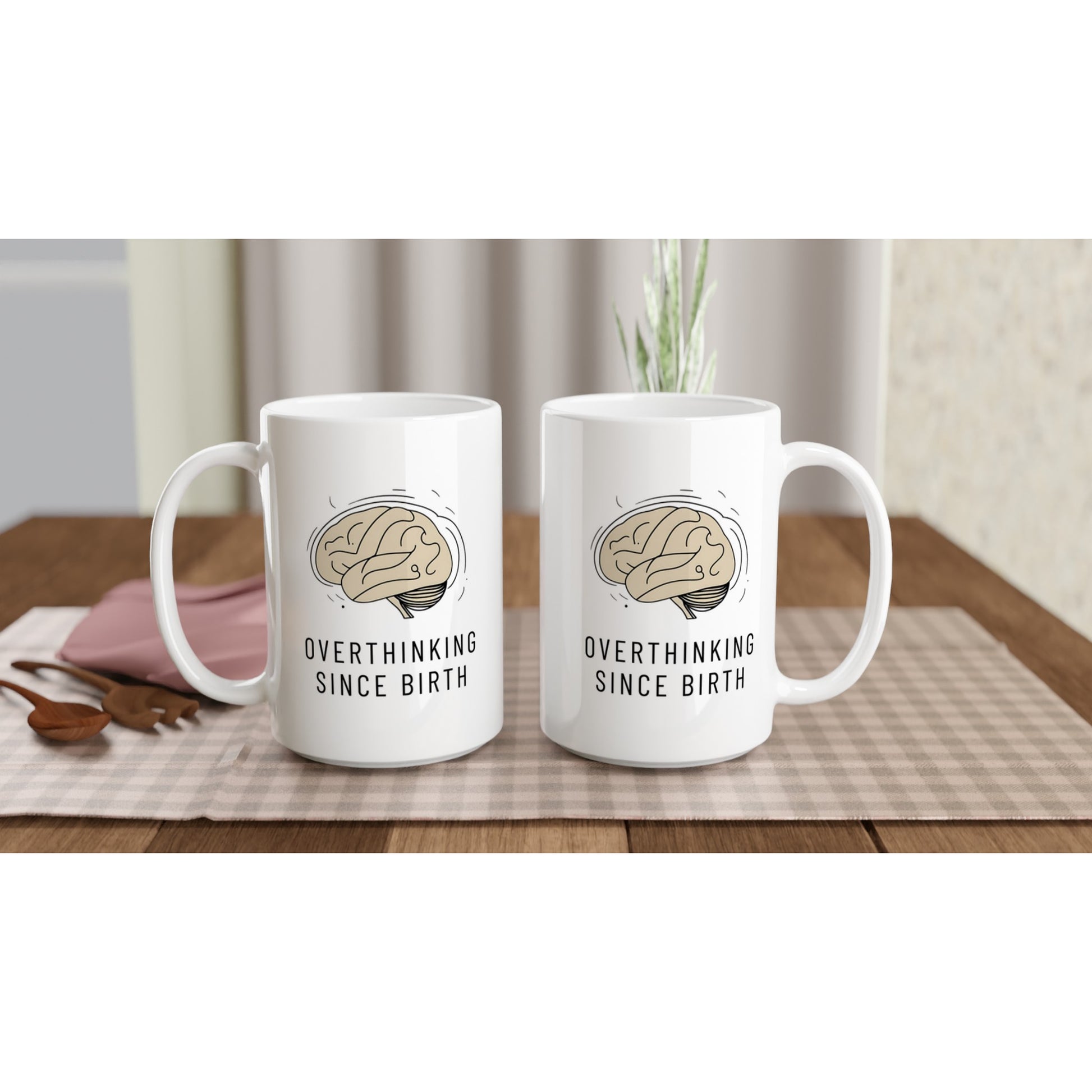 Two white mugs with brain graphic and 'Overthinking Since Birth' text on a wooden table.