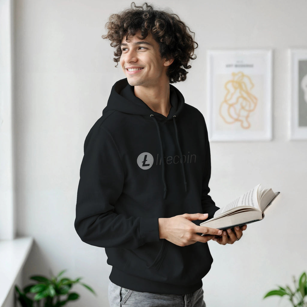 Man wearing a black hoodie with a logo, holding an open book indoors.