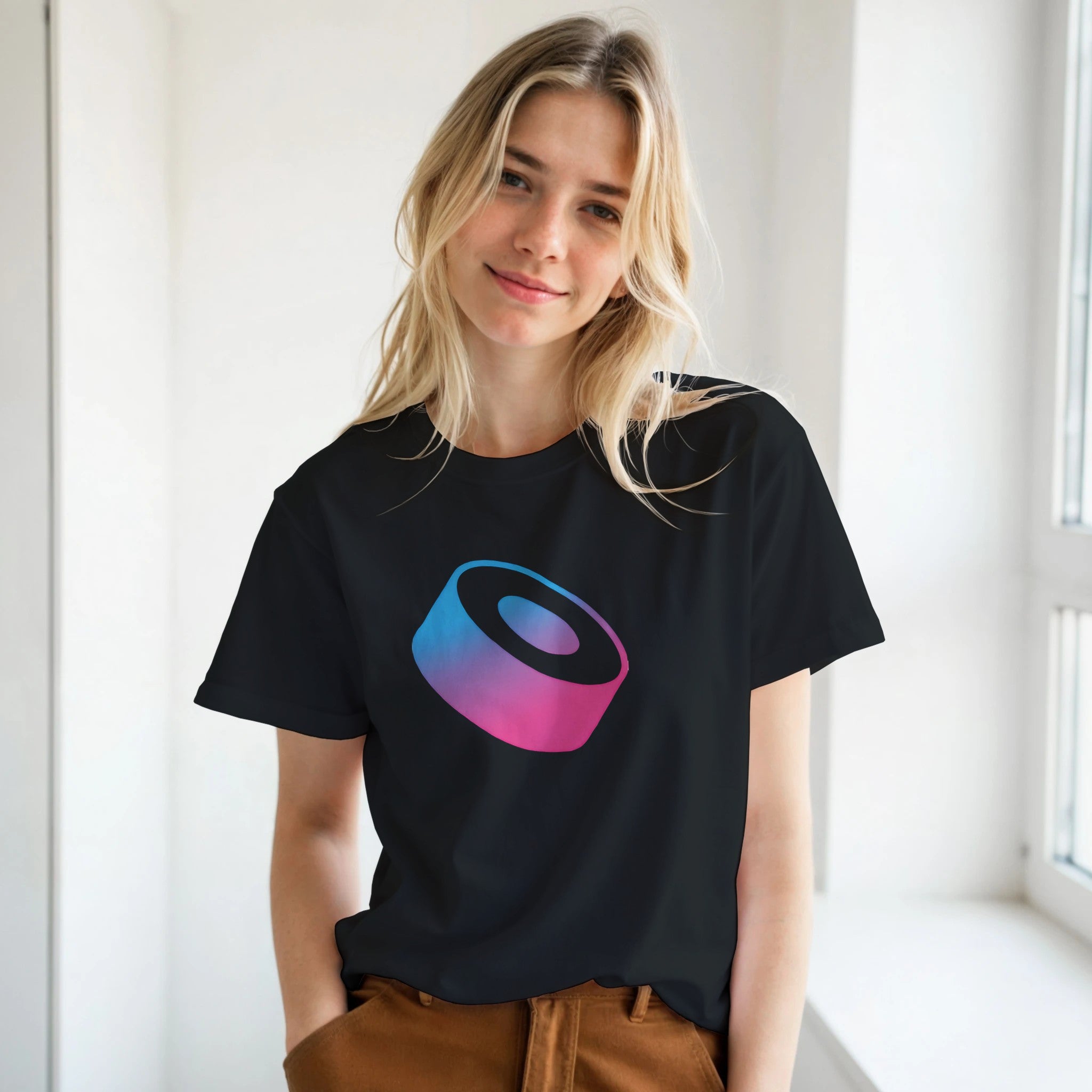 Person wearing a black t-shirt with a colorful logo in a bright room.