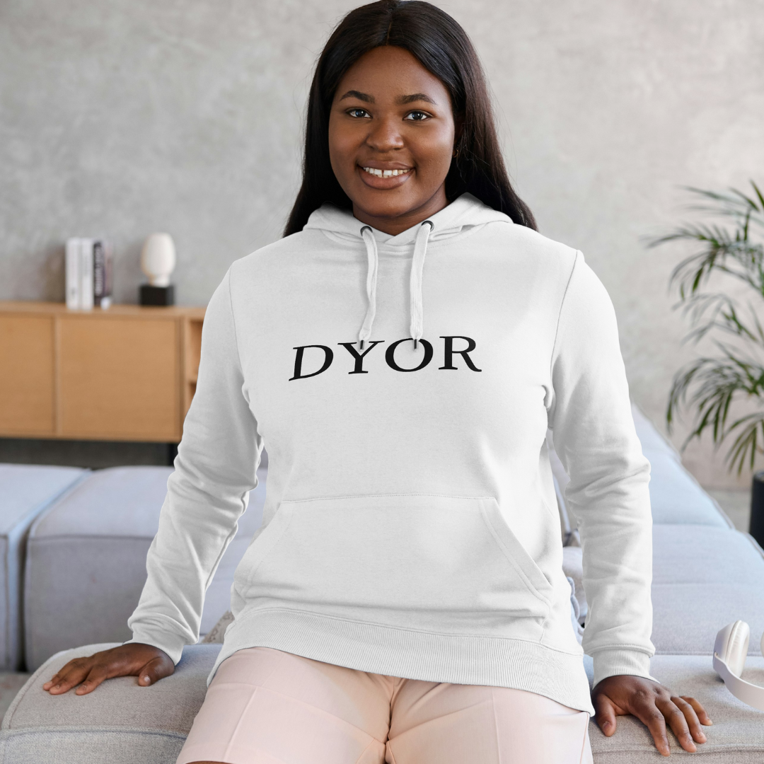 Woman wearing a white hoodie with 'DYOR' text in a living room setting