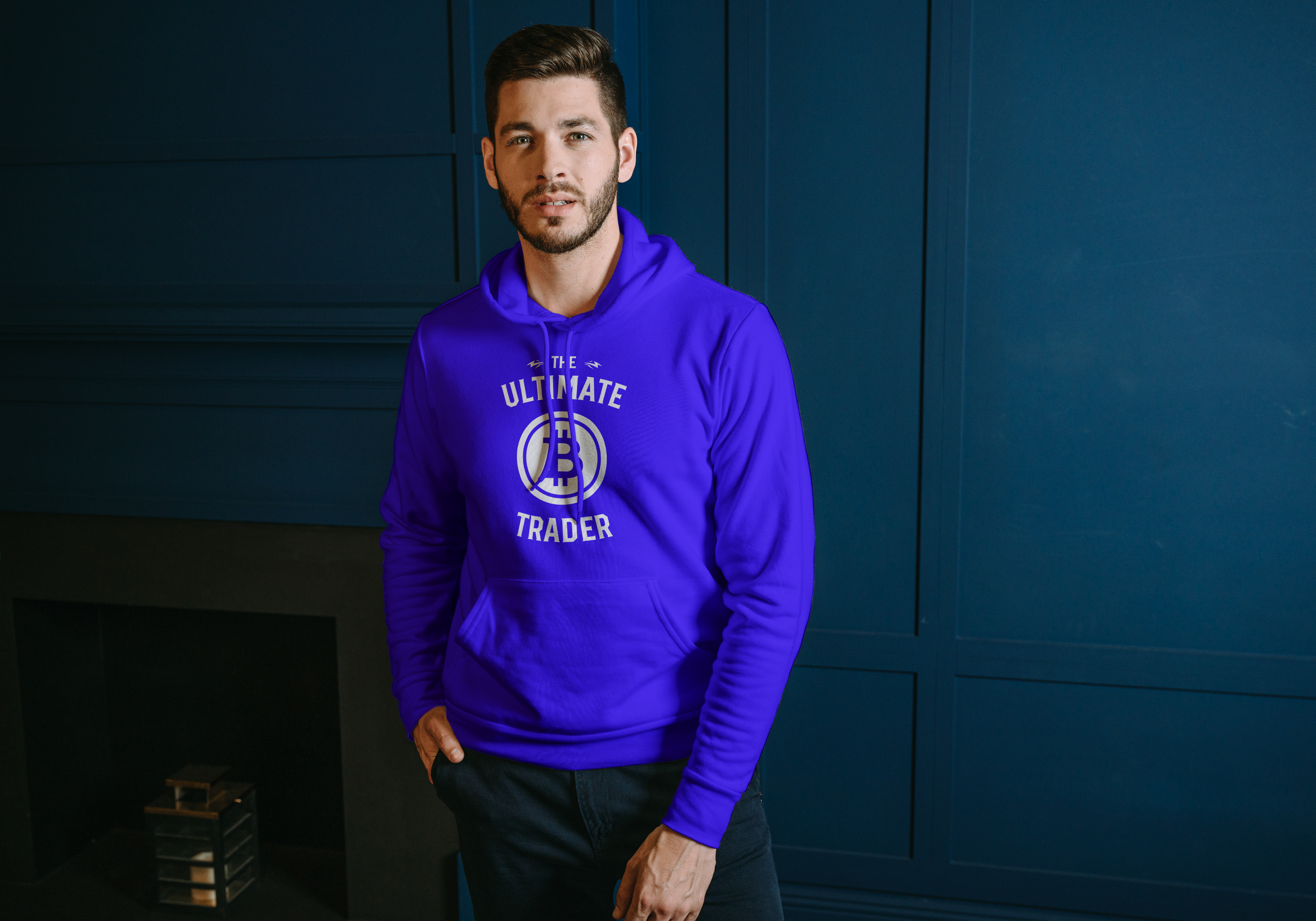 Man wearing a purple hoodie with 'The Ultimate Trader' design against a blue wall.