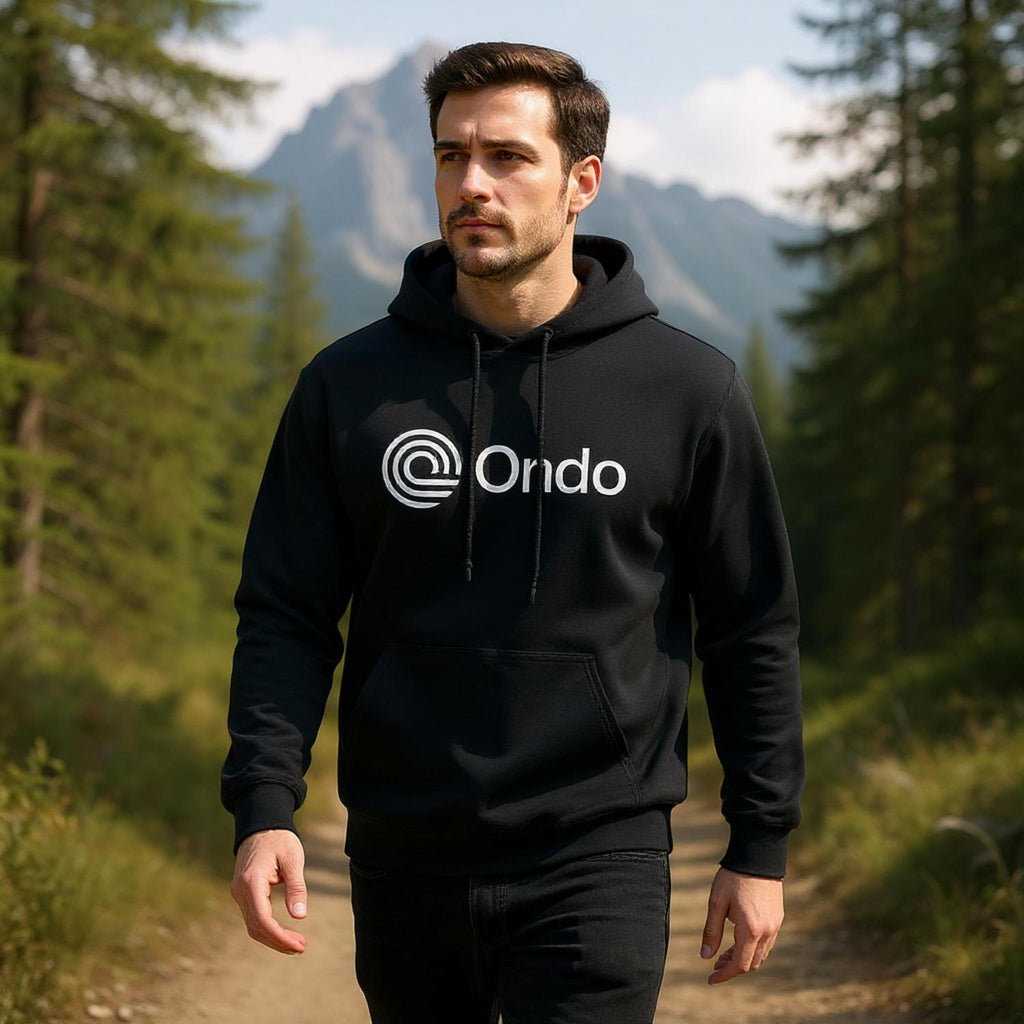 Man wearing a black hoodie with 'Ondo' logo in a forest setting