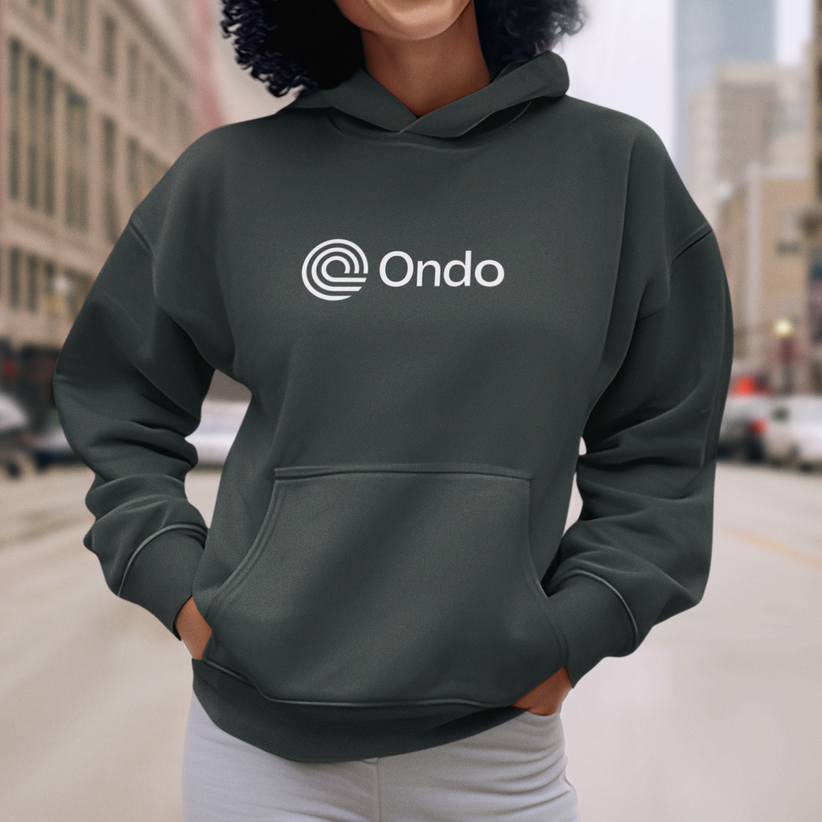 Person wearing a dark gray hoodie with 'Ondo' logo on a city street.