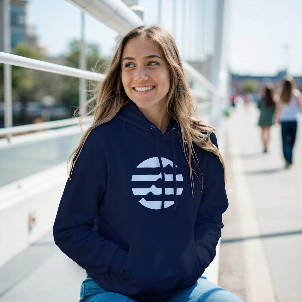 Woman wearing a navy hoodie with a logo, sitting outdoors on a sunny day.