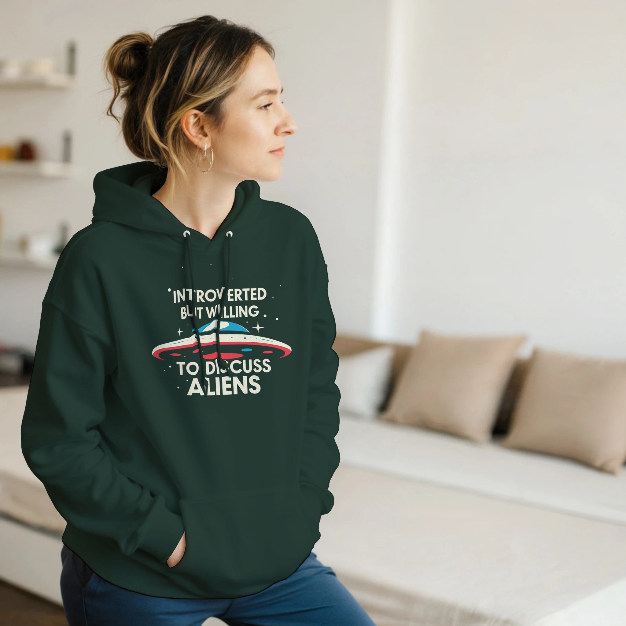 Person wearing a green hoodie with text and alien graphic in a living room.