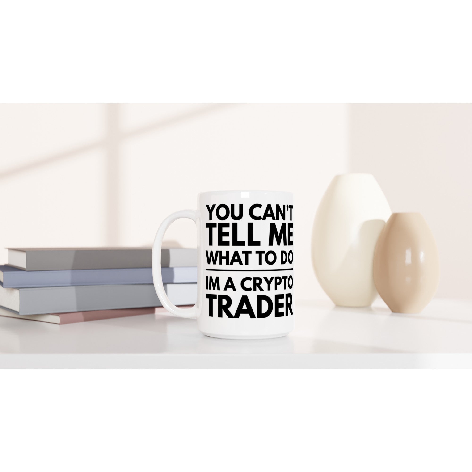 Mug with text 'You can't tell me what to do, I'm a crypto trader' on a white surface with books and decorative items.