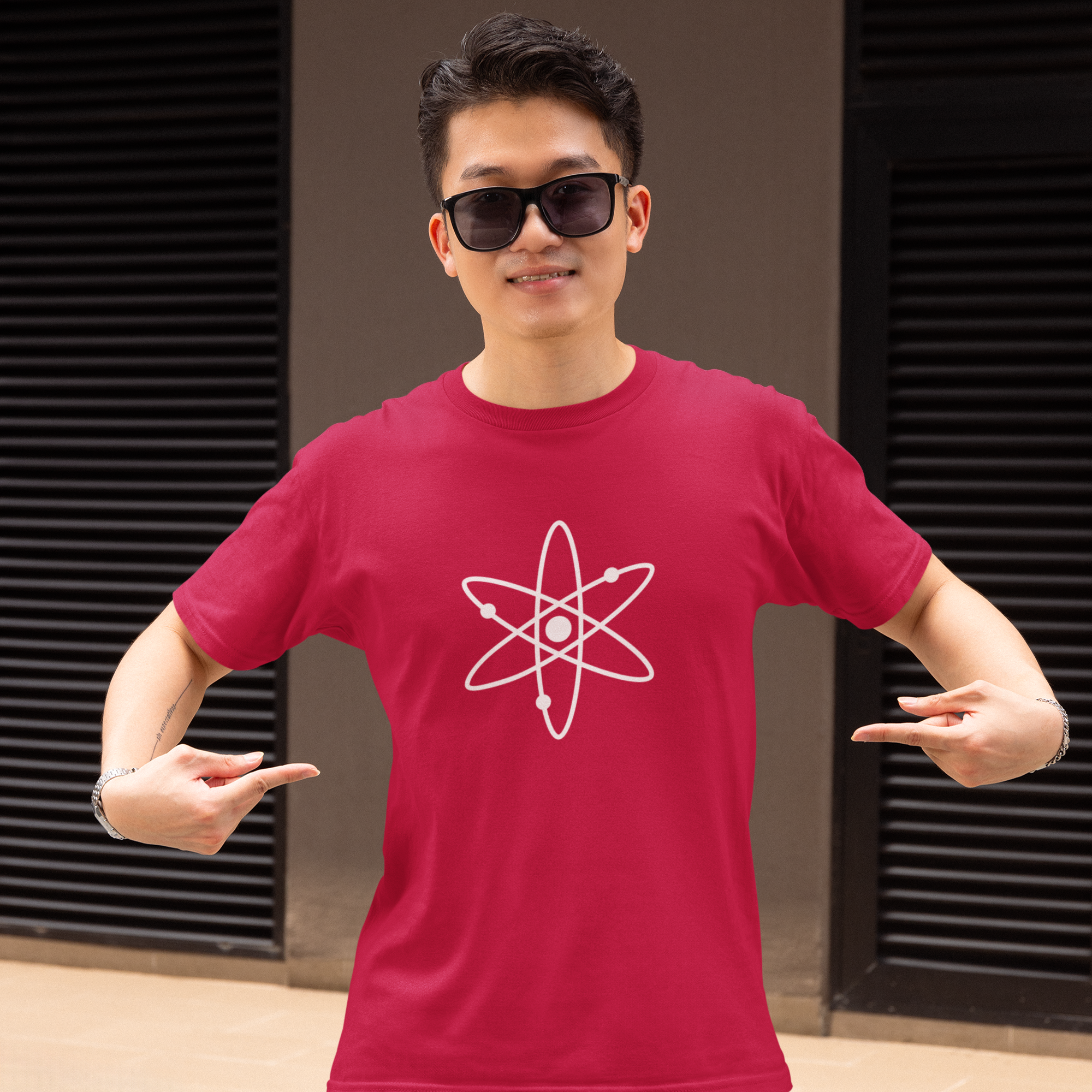 Person wearing a red t-shirt with an atom symbol design, standing against a dark background.