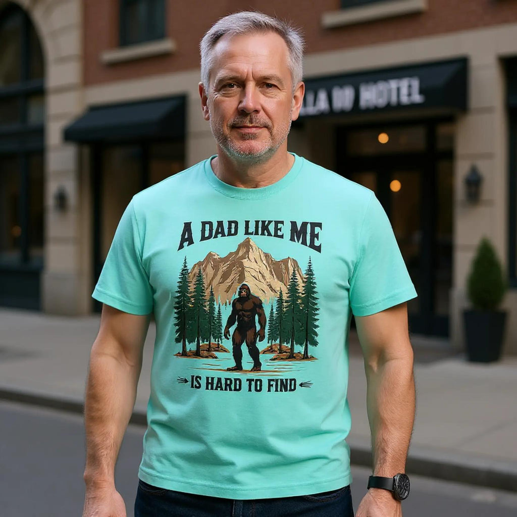 Man wearing a light blue t-shirt with a graphic and text, standing on a street.