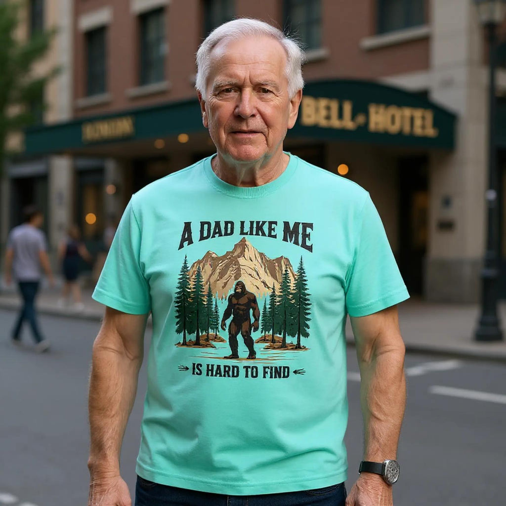 Man wearing a light blue t-shirt with a graphic and text, standing on a city street.