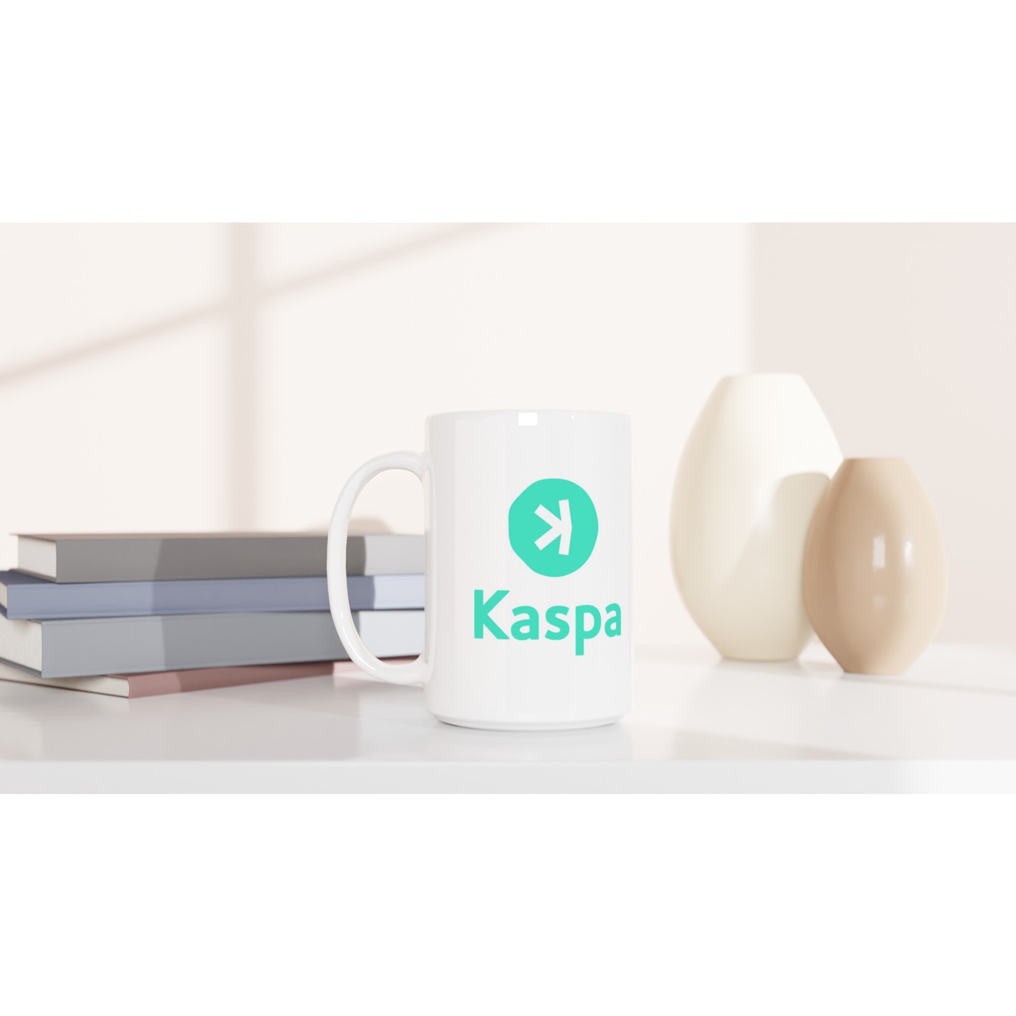 White mug with Kaspa logo on a white surface with books and decorative items.