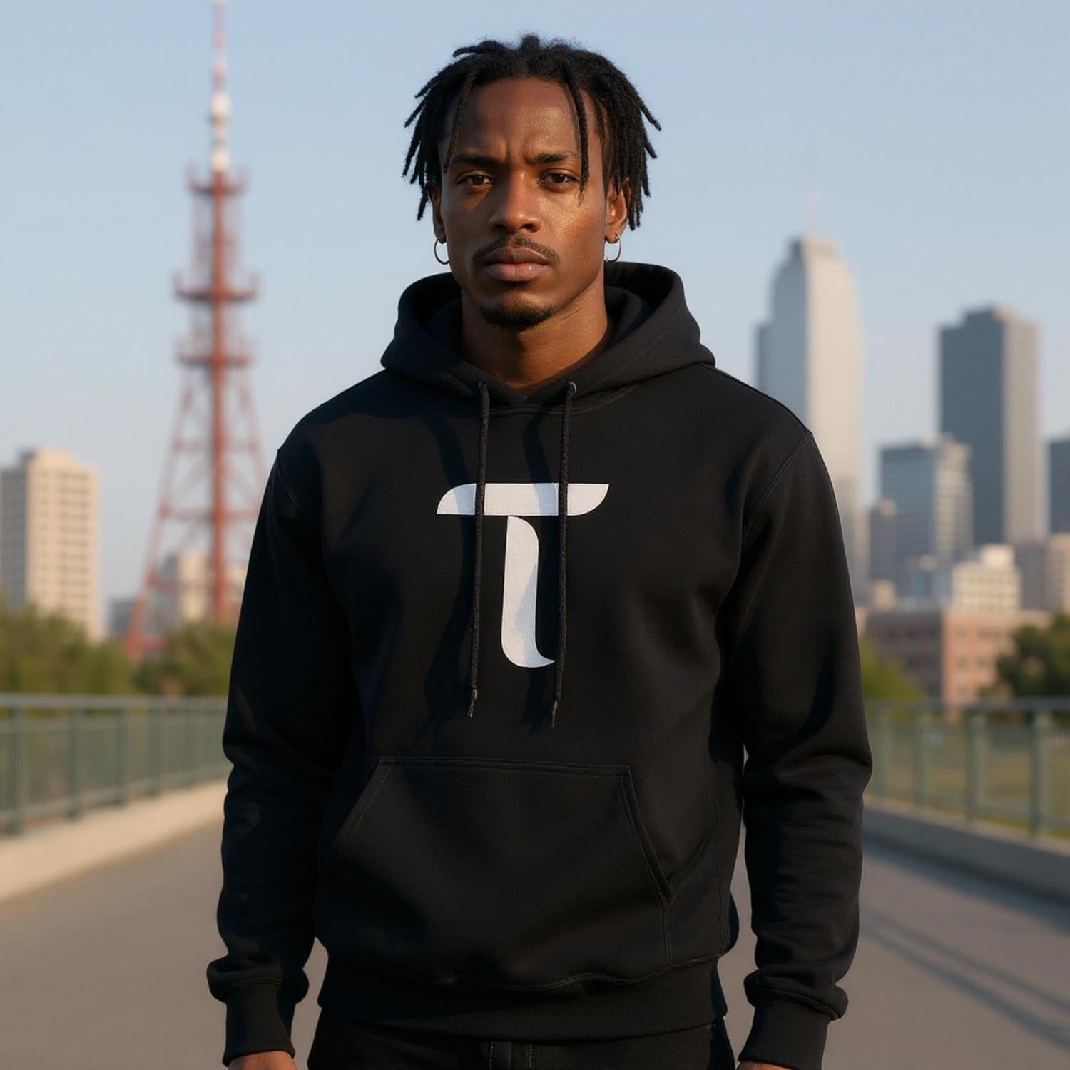Person wearing a black hoodie with a white logo in an urban setting