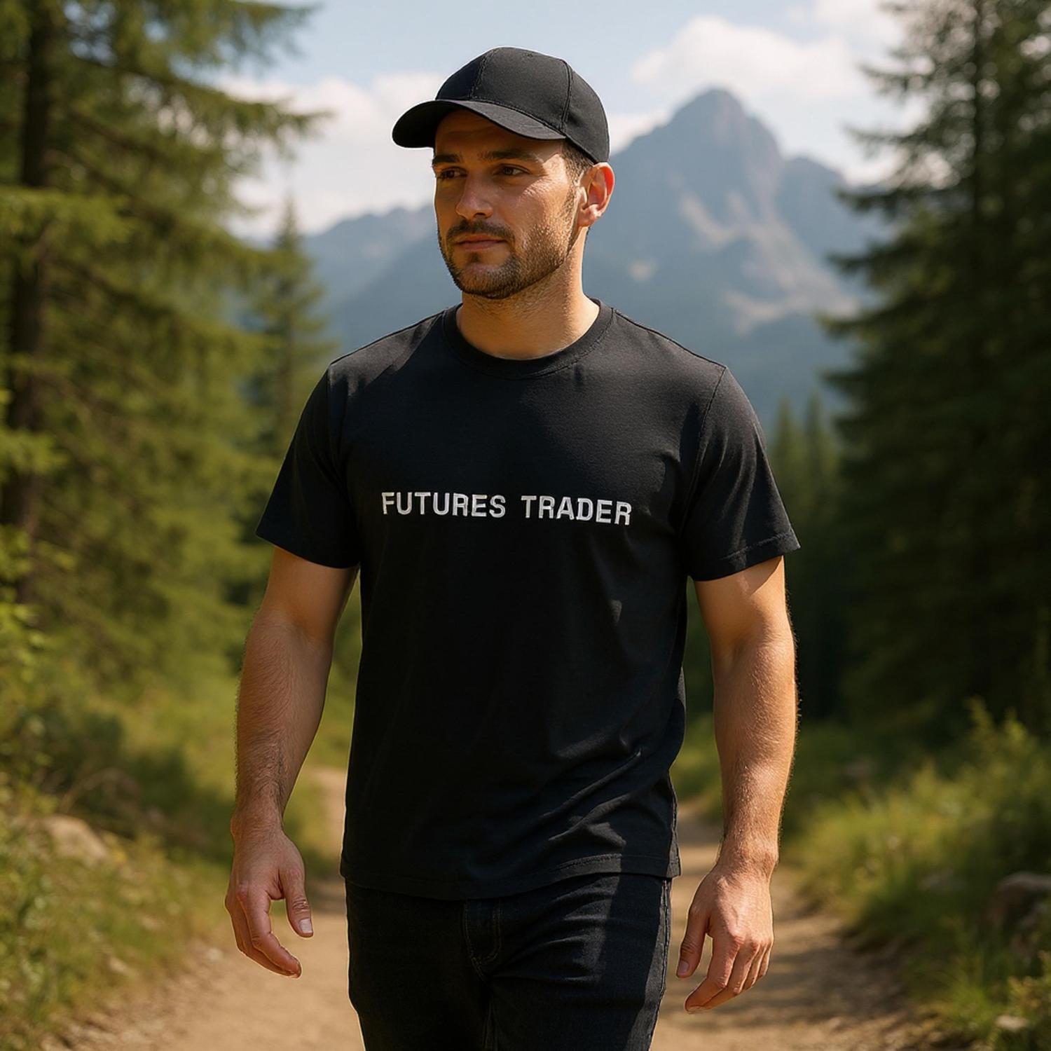 Man wearing a black 'Futures Trader' t-shirt in a forest with mountains in the background