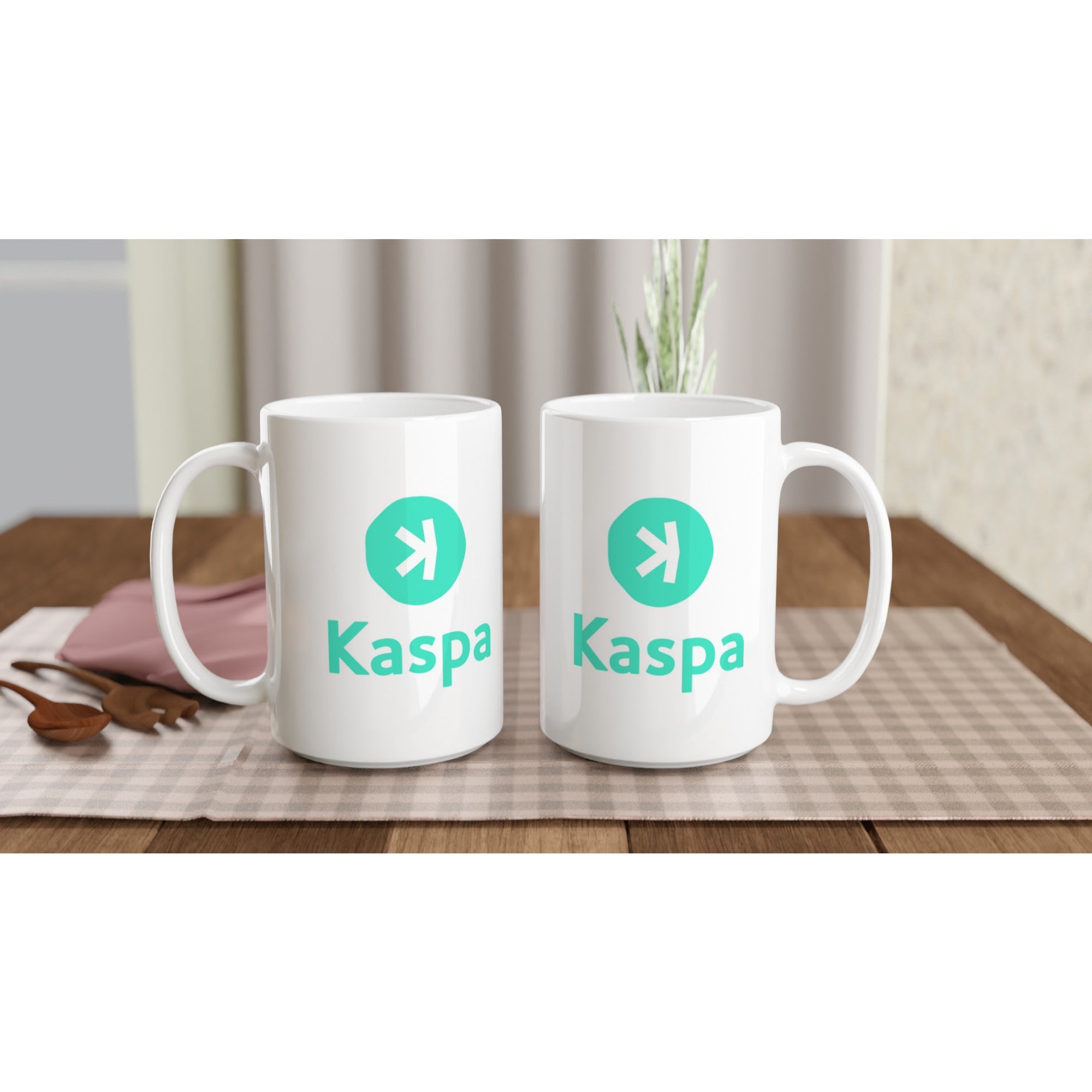 Two white mugs with Kaspa logo on a wooden table with a checkered tablecloth.