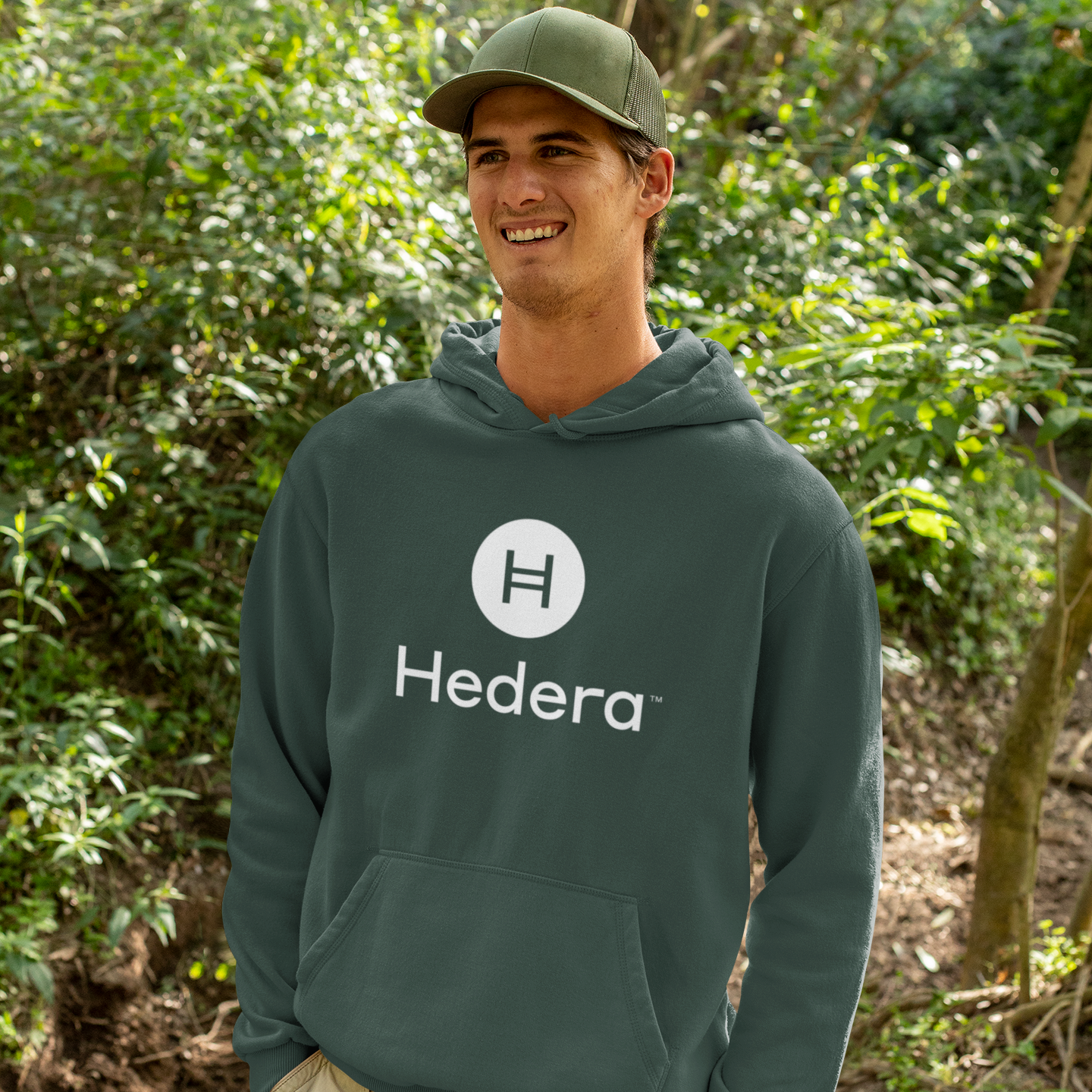 Person wearing a Hedera hoodie in a forest setting
