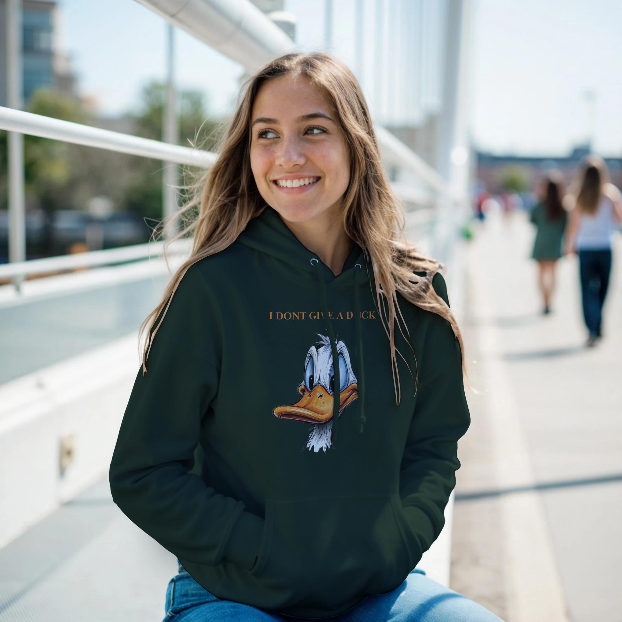 Woman wearing a black hoodie with a graphic design, sitting outdoors on a sunny day.
