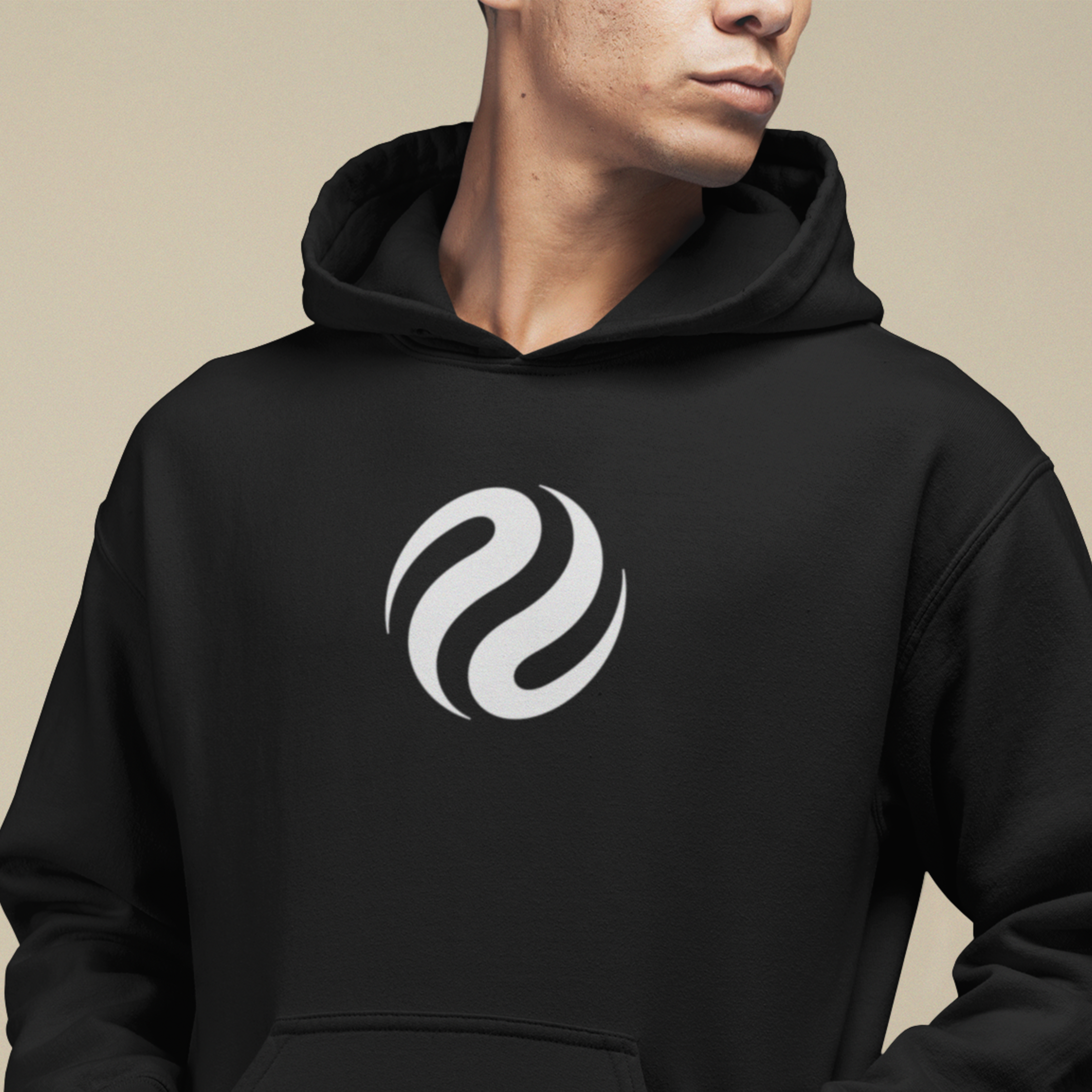 Person wearing a black hoodie with a white logo on a beige background