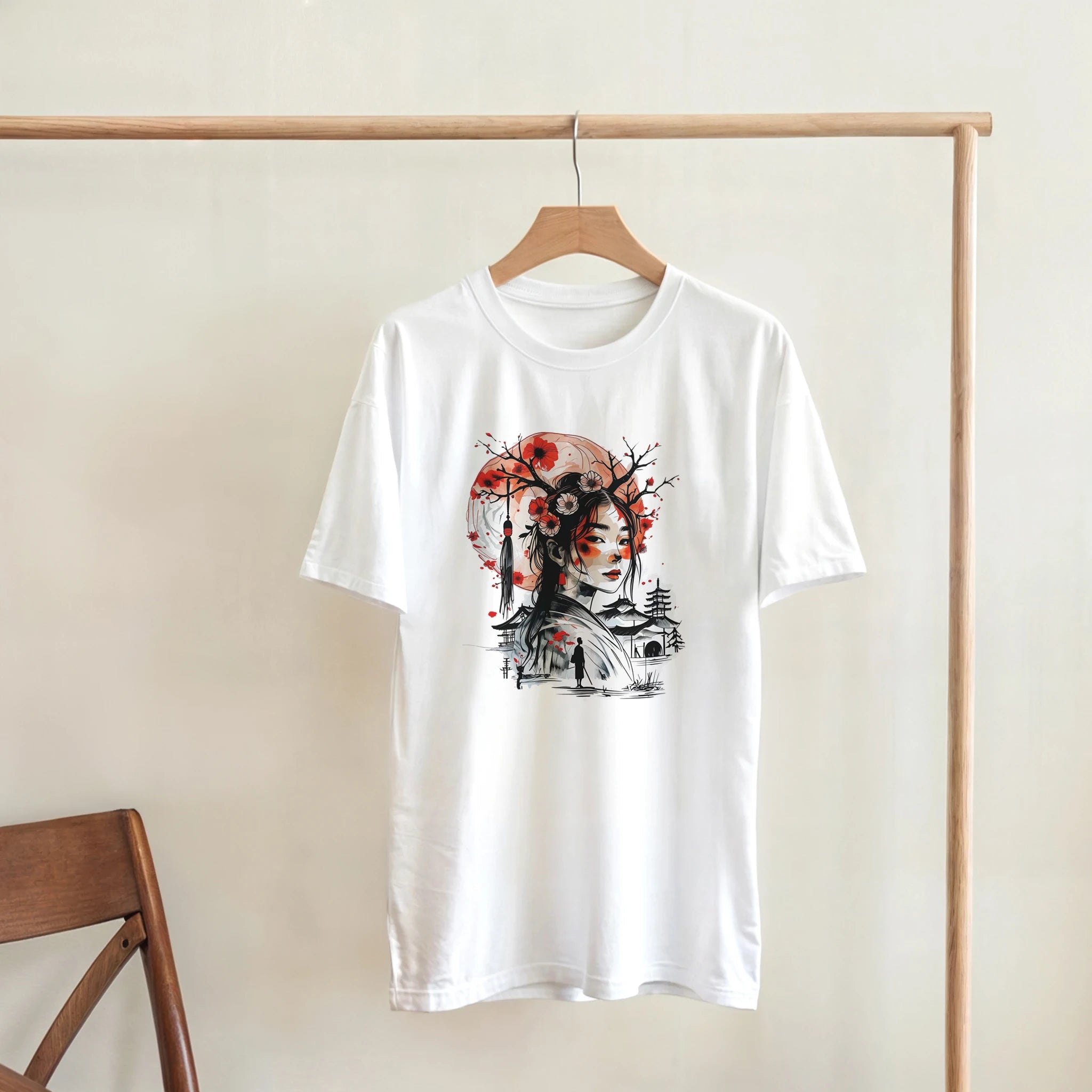 White t-shirt with a graphic design on a wooden hanger against a beige wall.