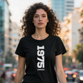 Woman wearing a black t-shirt with '1975 Legend' text on a city street.