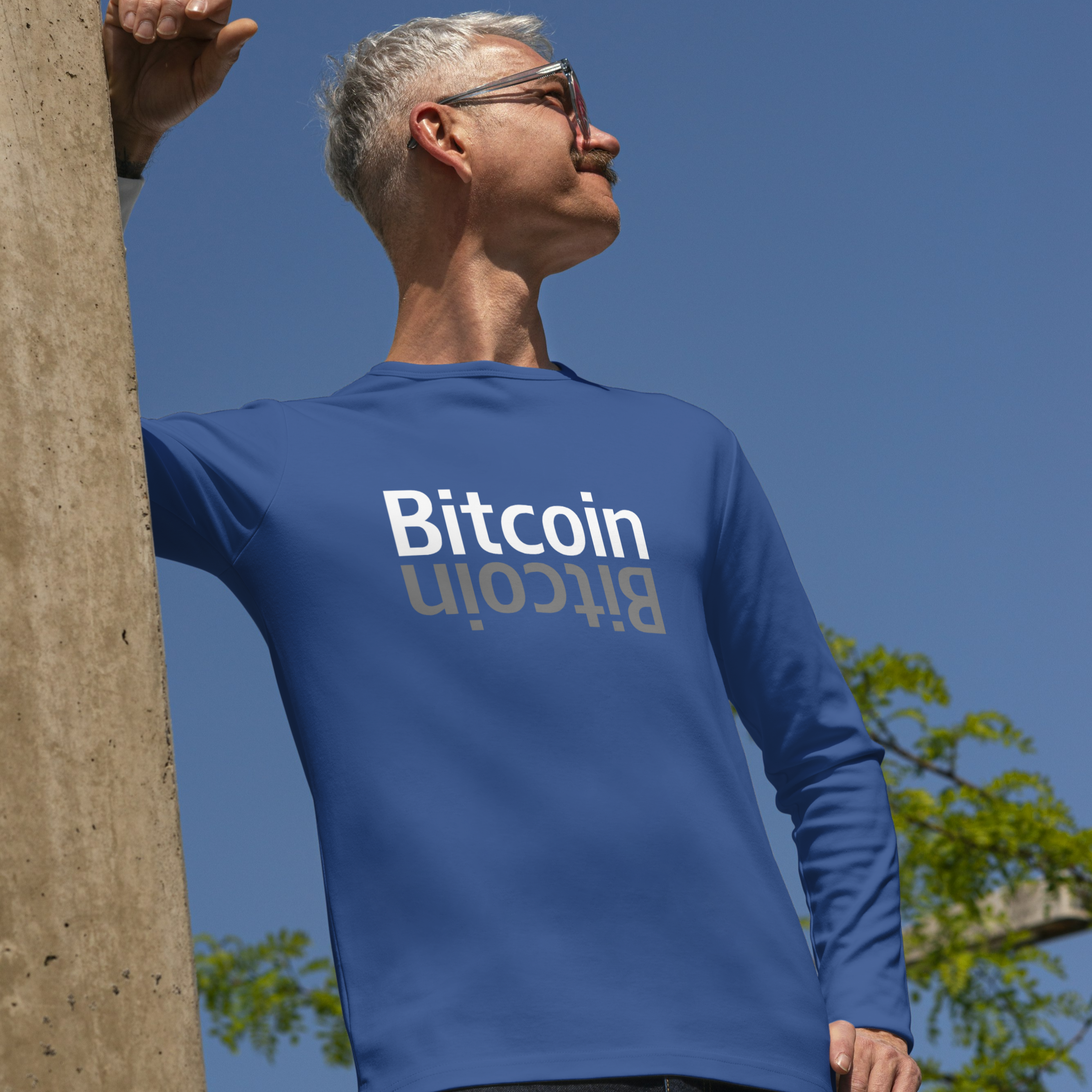 Person wearing a blue 'Bitcoin' t-shirt against a clear blue sky.