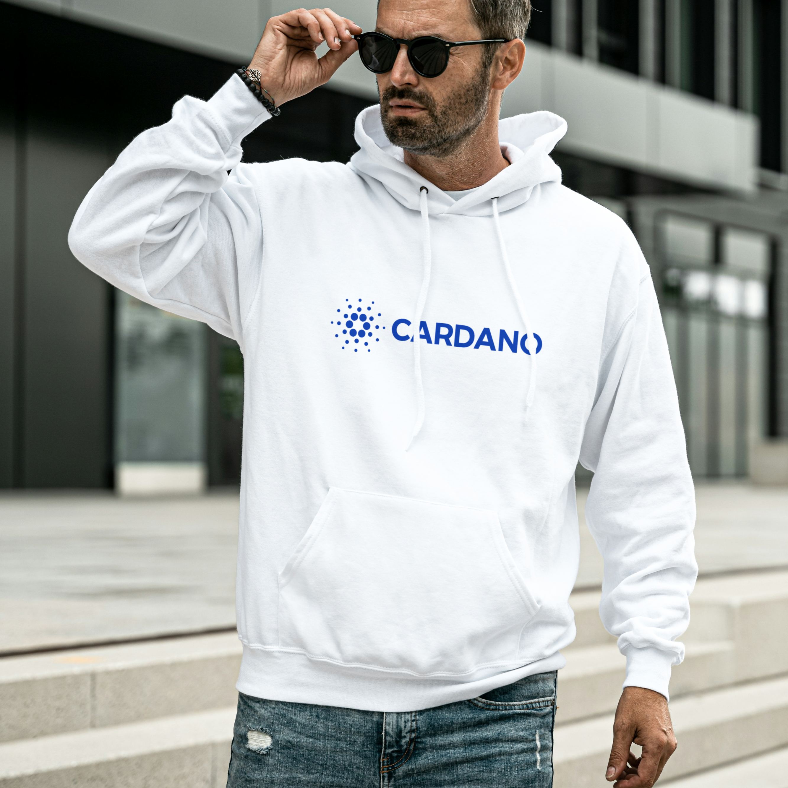 Man wearing a white hoodie with Cardano logo outdoors