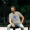 Man wearing a t-shirt with 'Cardano' logo sitting outdoors.