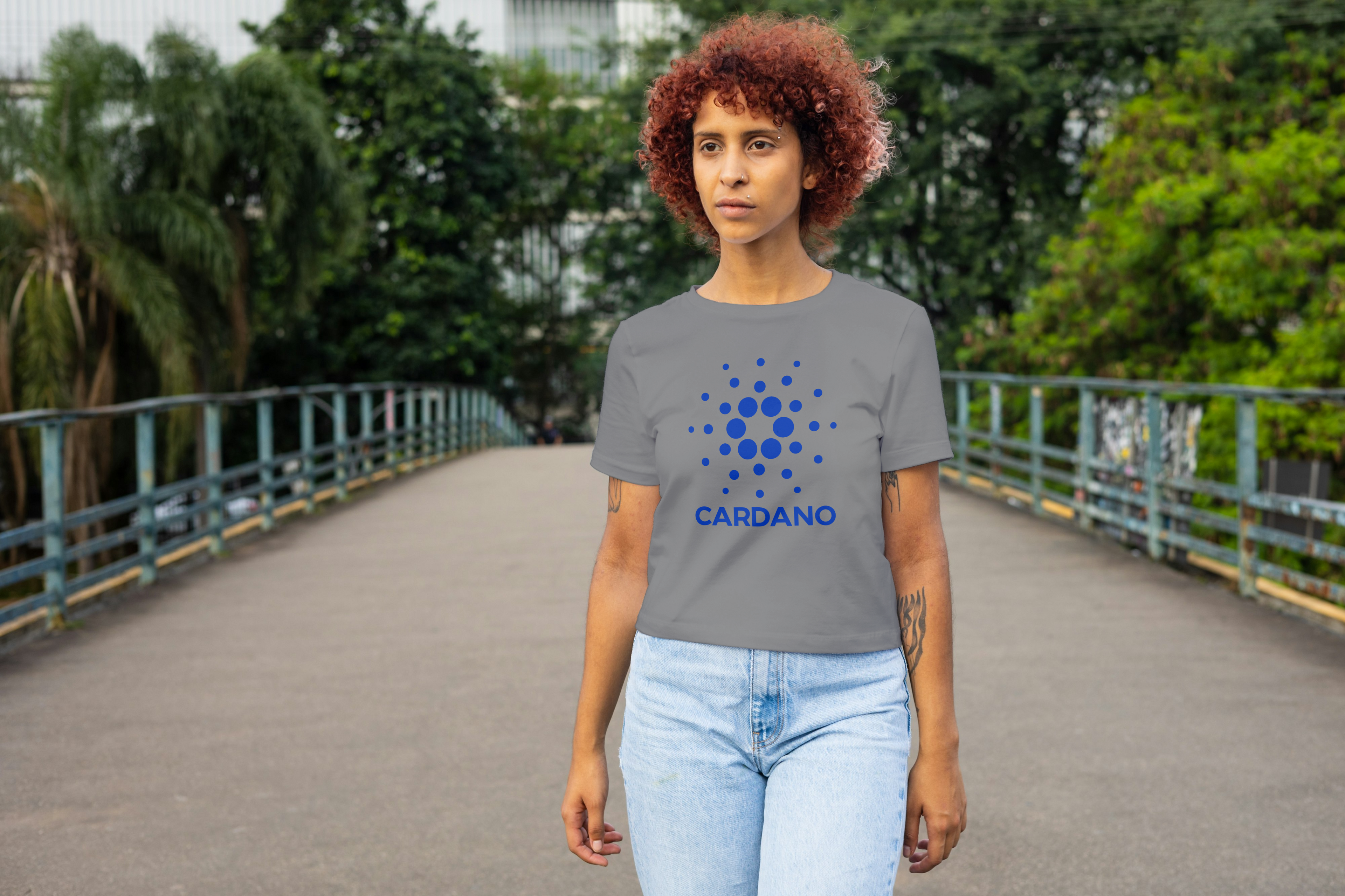 Person wearing a gray t-shirt with Cardano logo outdoors