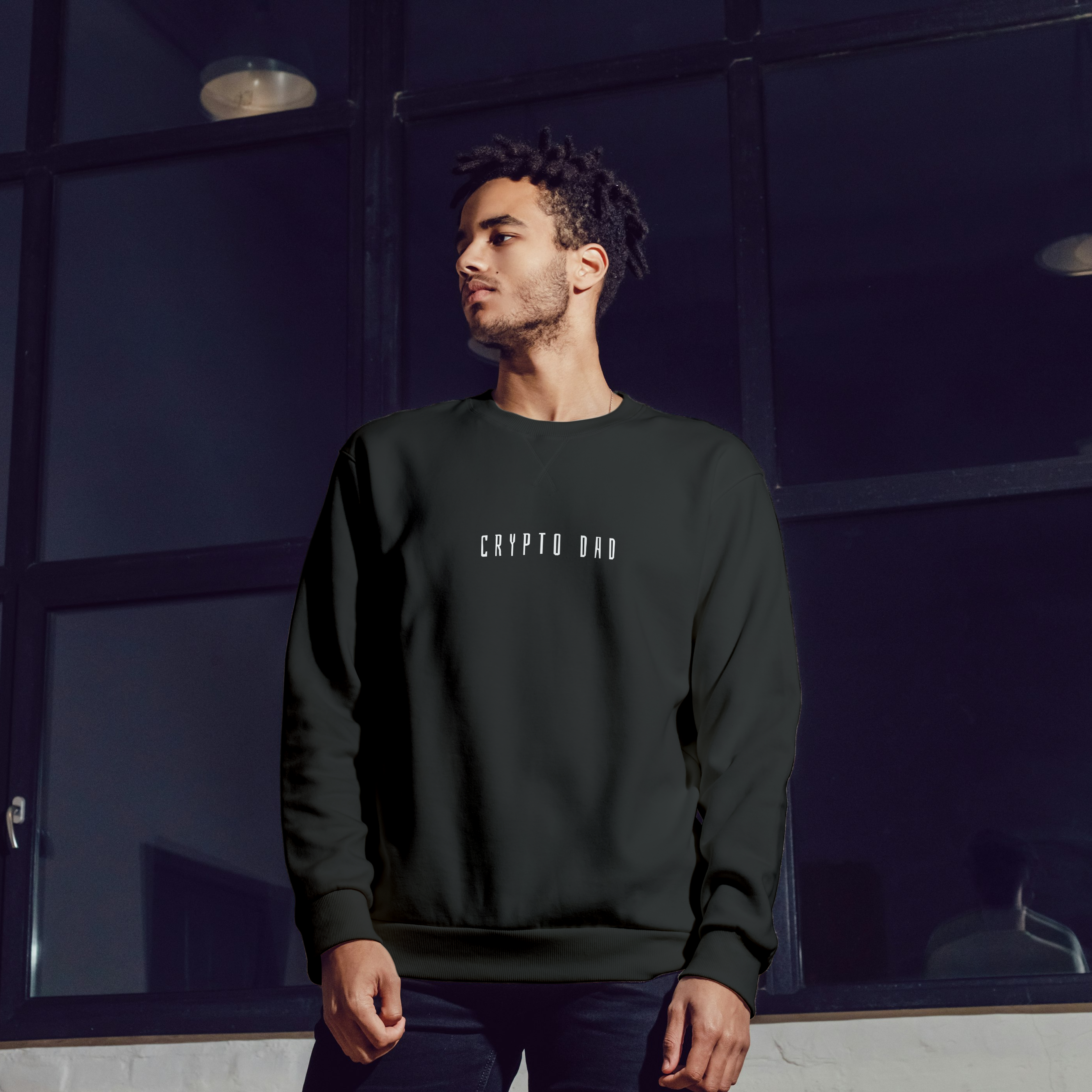 Man wearing a dark green sweatshirt with text, standing in front of a reflective surface.