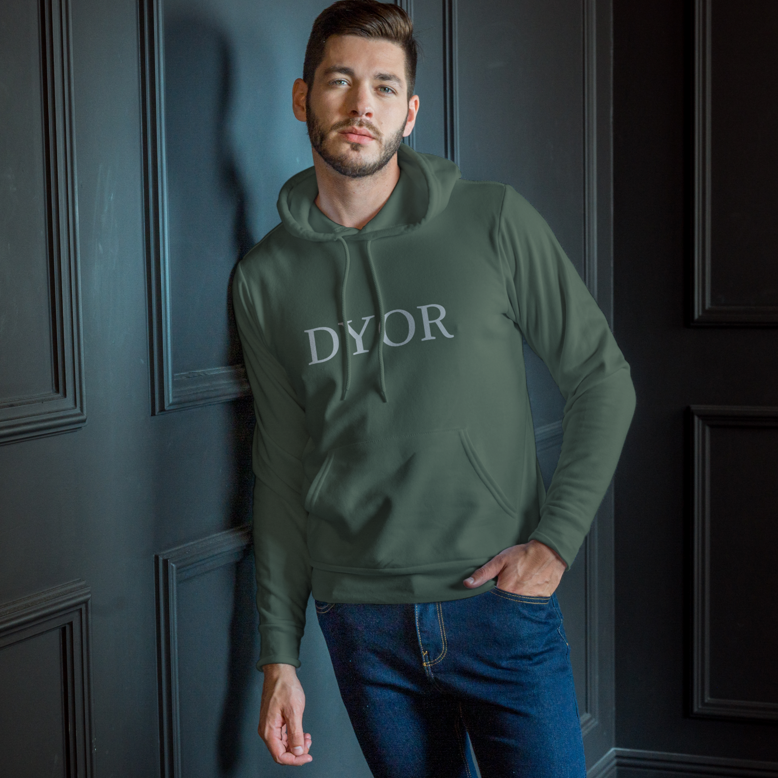 Man wearing a green hoodie with 'DYOR' text against a dark paneled wall