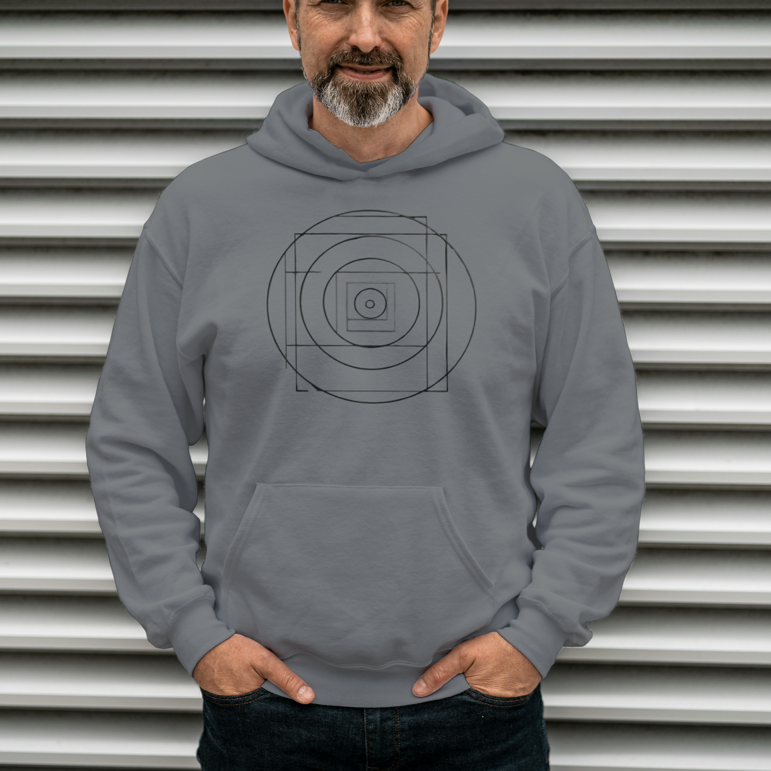 Man wearing a gray hoodie with a geometric design in front of a metallic background