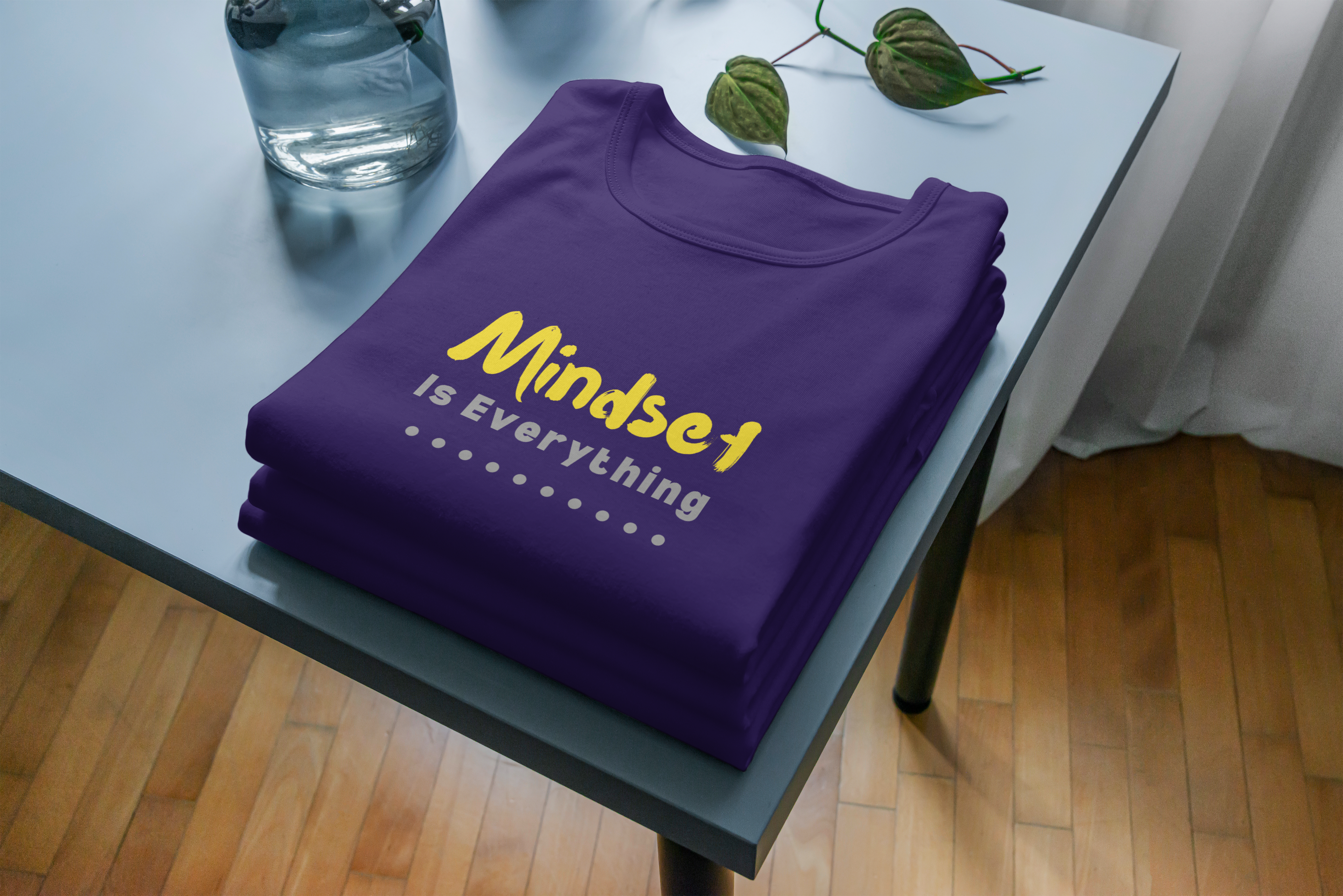 Purple t-shirt with 'Mindset is Everything' text on a table.