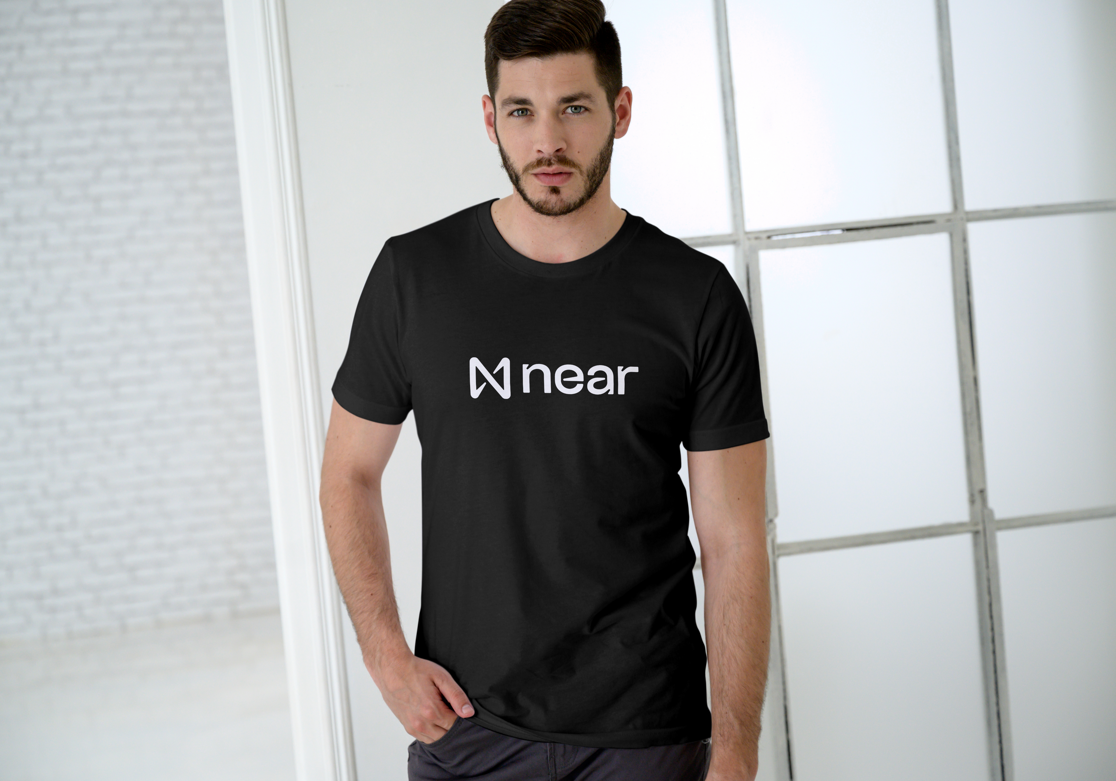 Man wearing a black t-shirt with 'near' logo in a modern indoor setting