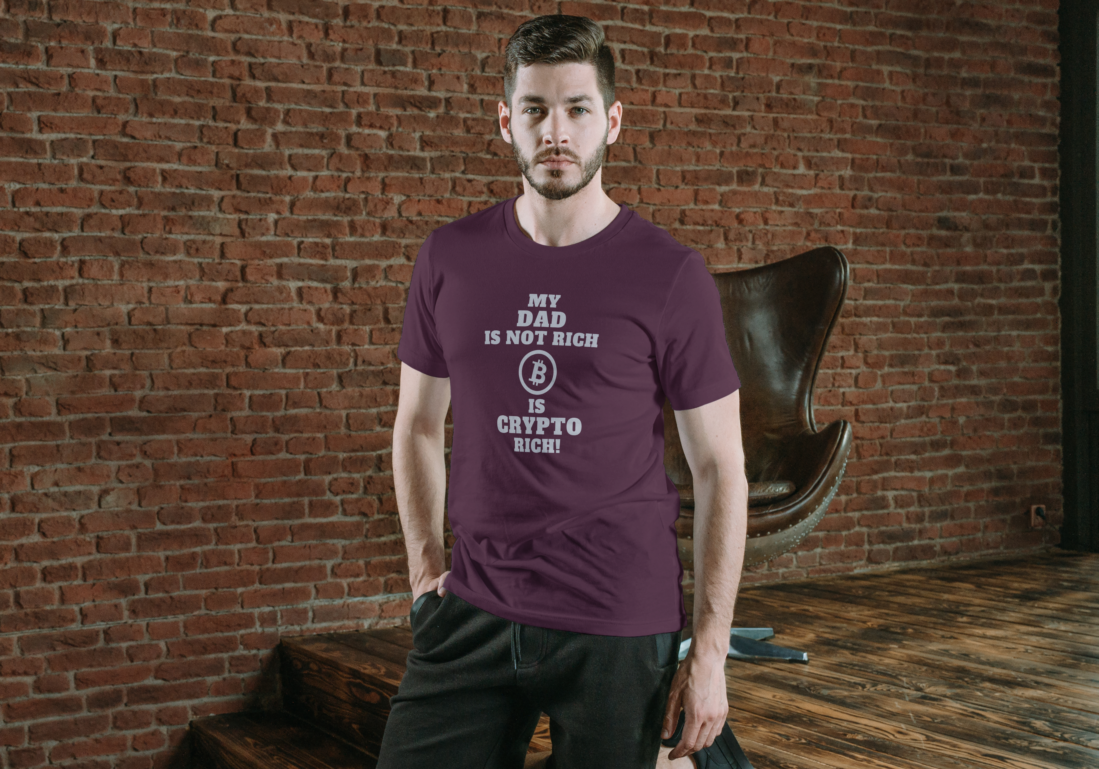Man wearing a purple t-shirt with text standing against a brick wall.