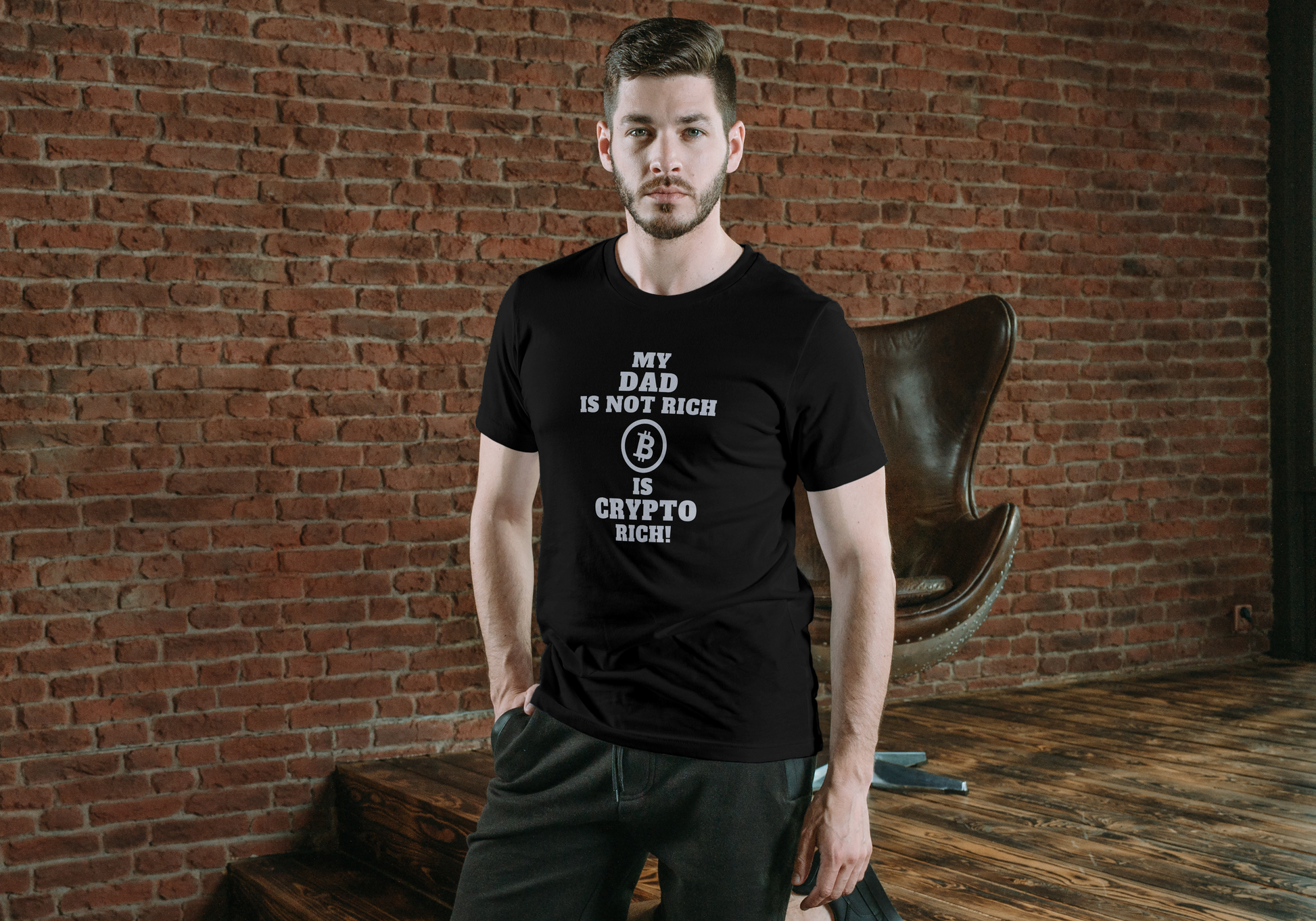 Man wearing a black t-shirt with text standing against a brick wall.