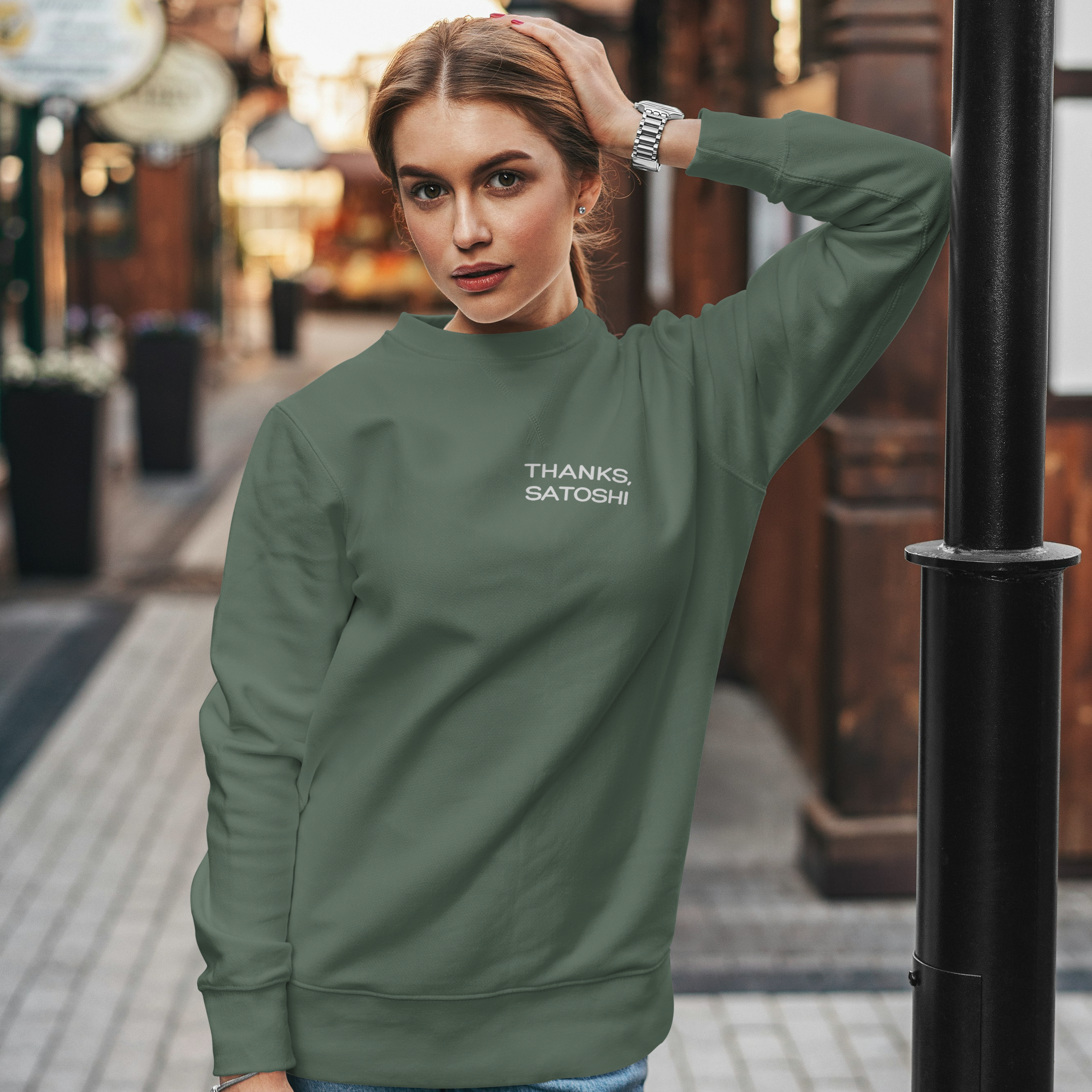 Woman wearing a green sweatshirt with text on it, standing on a street.