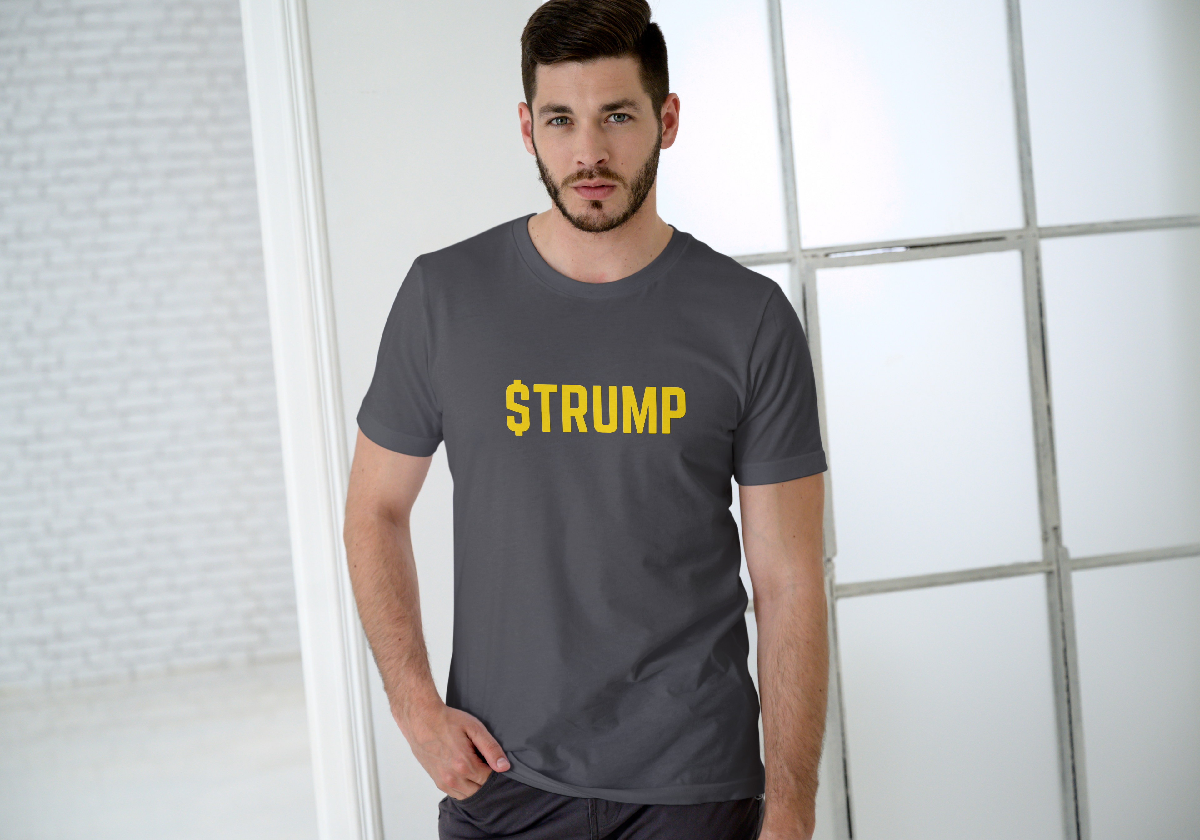 Man wearing a gray t-shirt with '$TRUMP' printed in yellow.