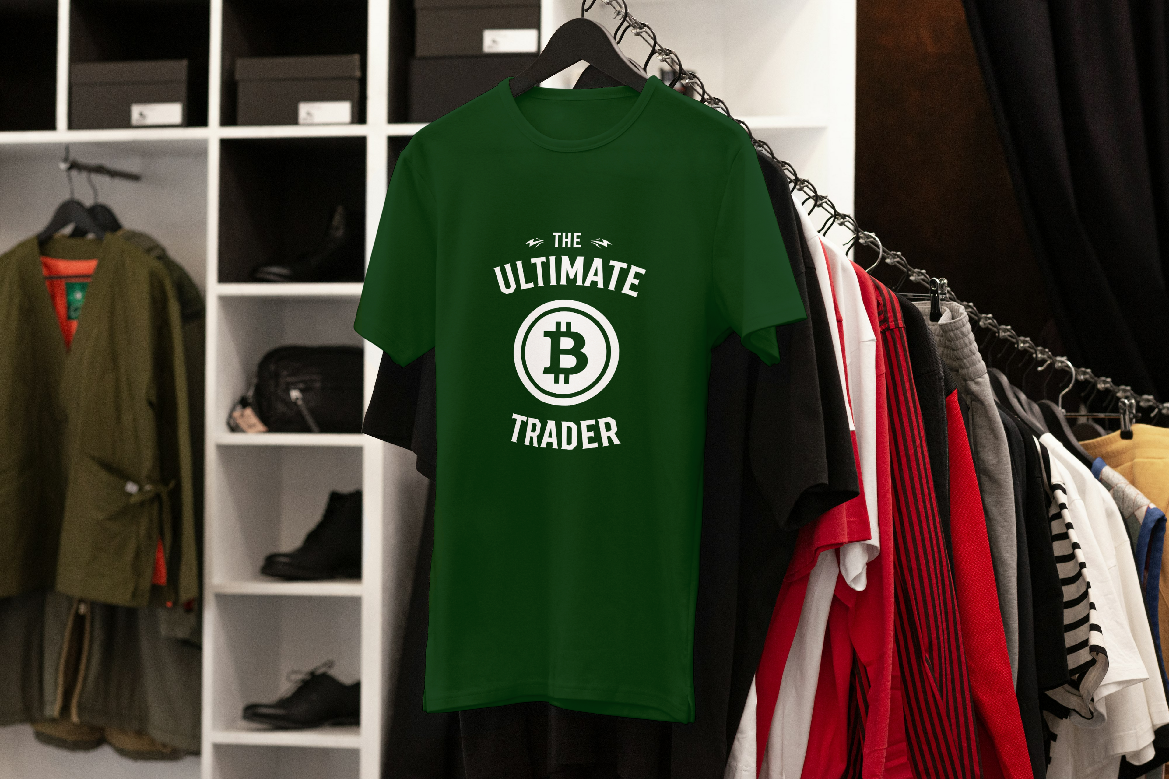 Green t-shirt with 'The Ultimate Trader' design on a rack with clothing in a store.