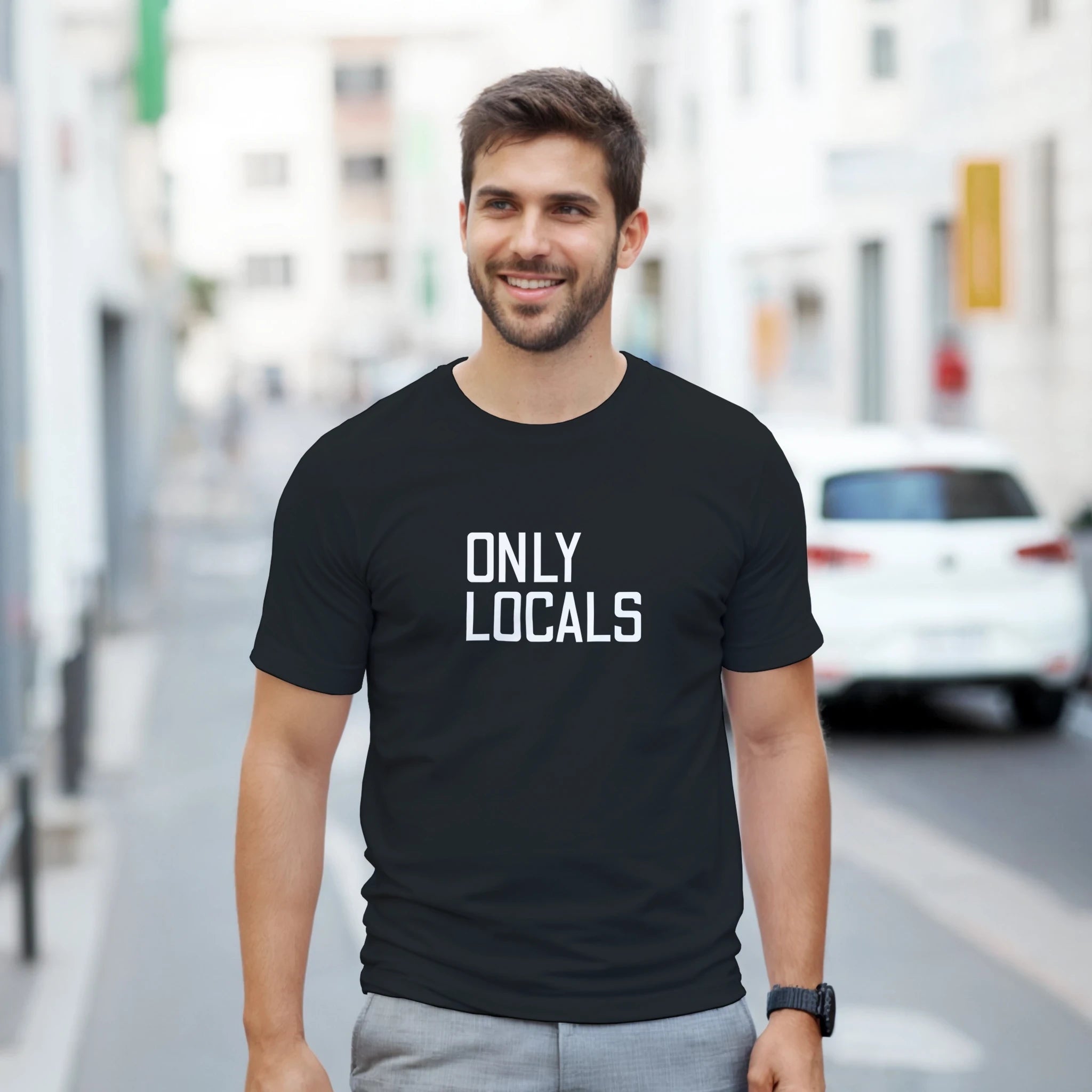Man wearing a black t-shirt with 'ONLY LOCALS' text on a city street.