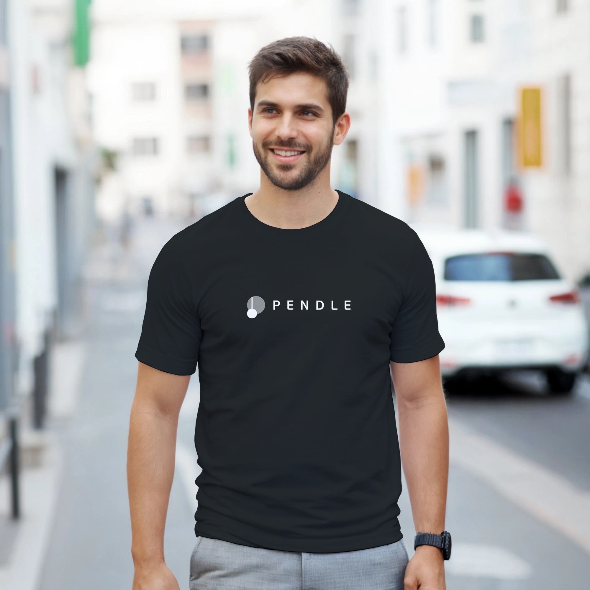 Man wearing a black t-shirt with 'Pendle' logo on a city street