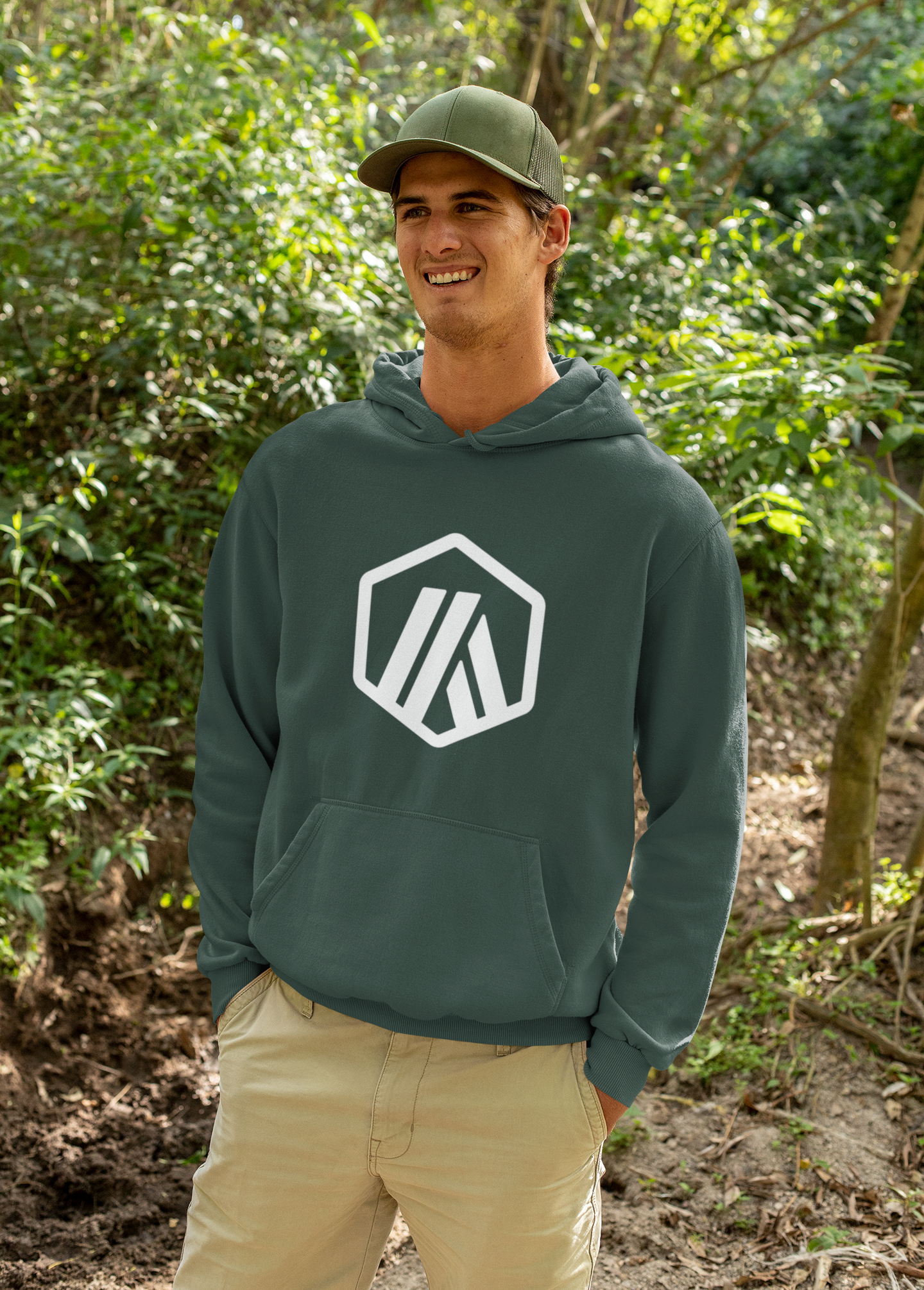 Man wearing a green hoodie with a logo in a forest setting