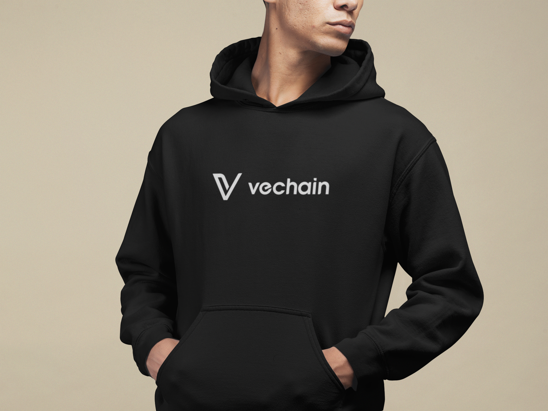 Person wearing a black hoodie with Vechain logo on a beige background