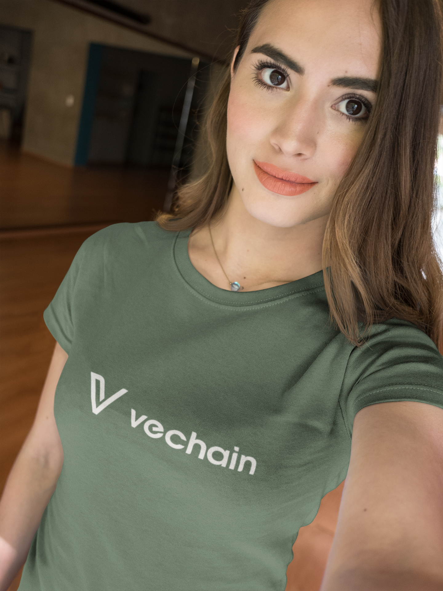 Woman wearing a green t-shirt with 'vechain' logo indoors.