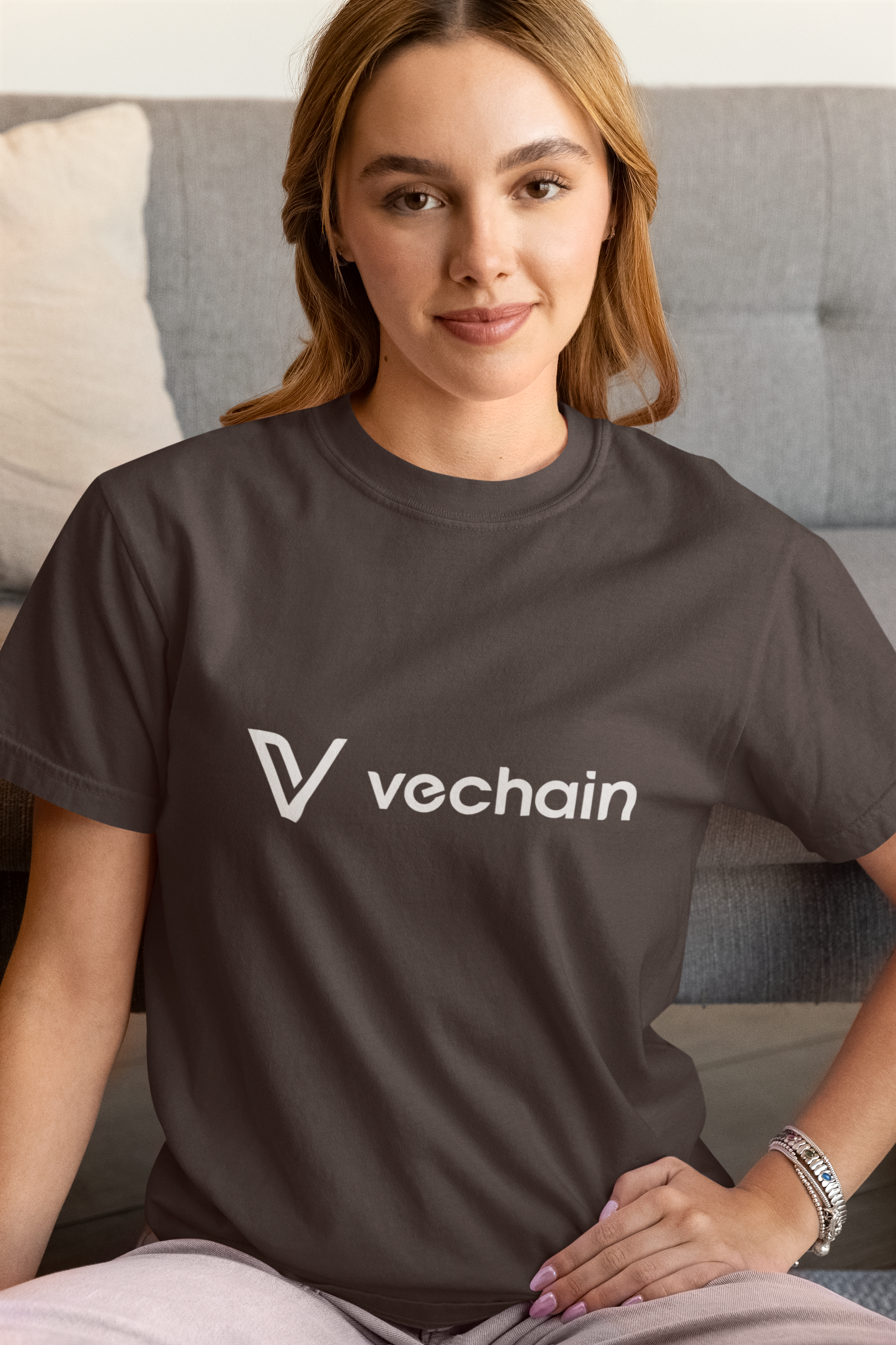 Woman wearing a black t-shirt with 'vechain' logo sitting on a couch.